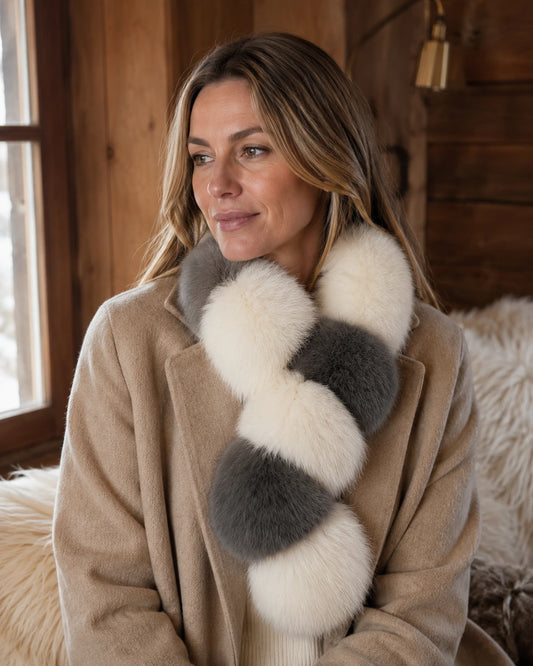 Woman wearing a charcoal and ivory genuine fur scarf with a camel coat in a winter cabin