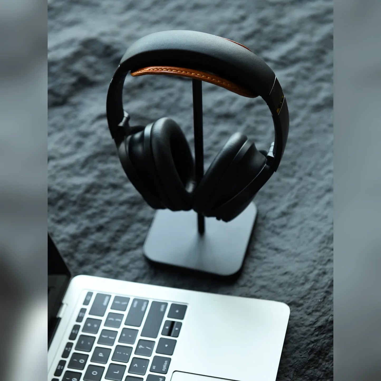 Black leather headphone stand beside laptop on desk