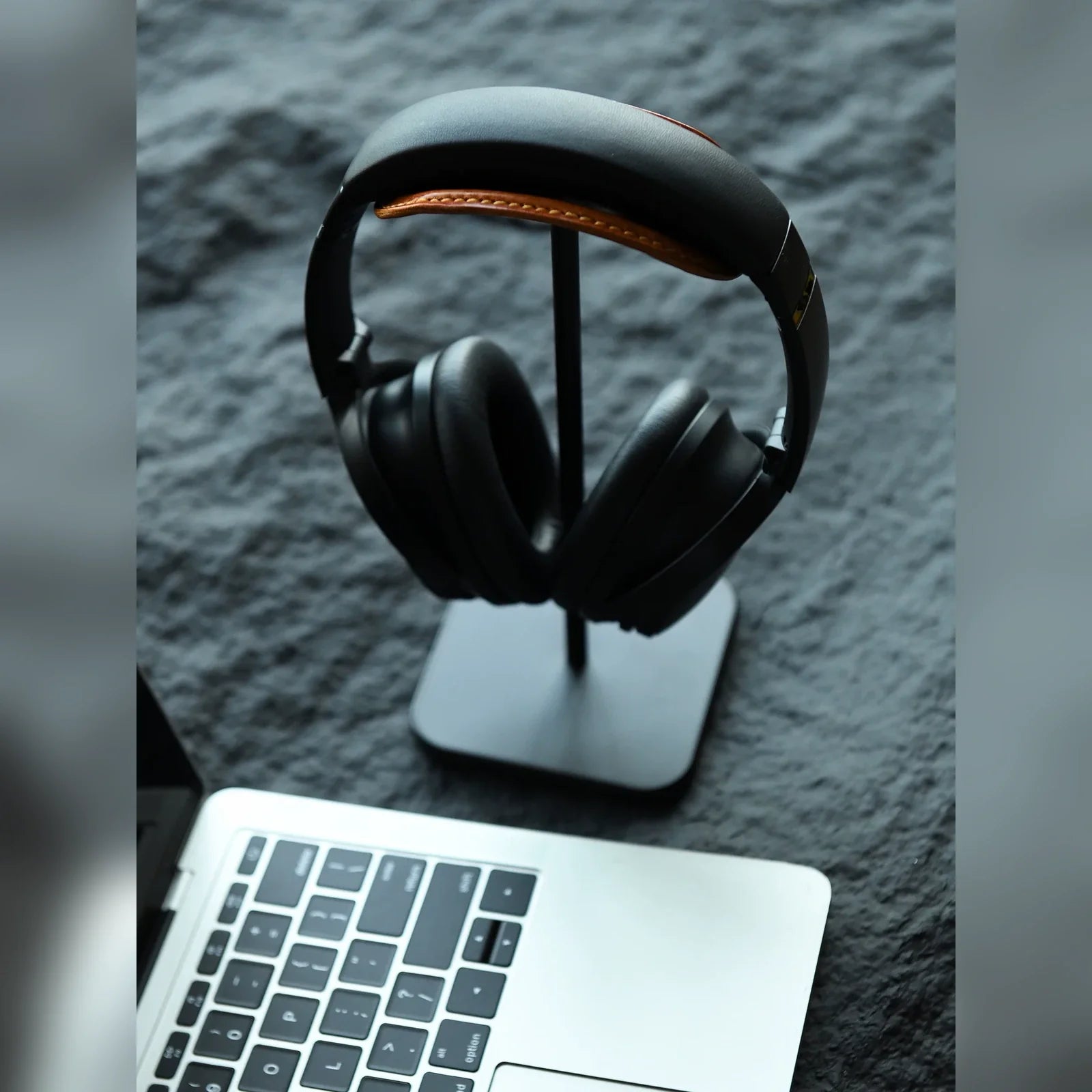 Black leather headphone stand beside laptop on desk