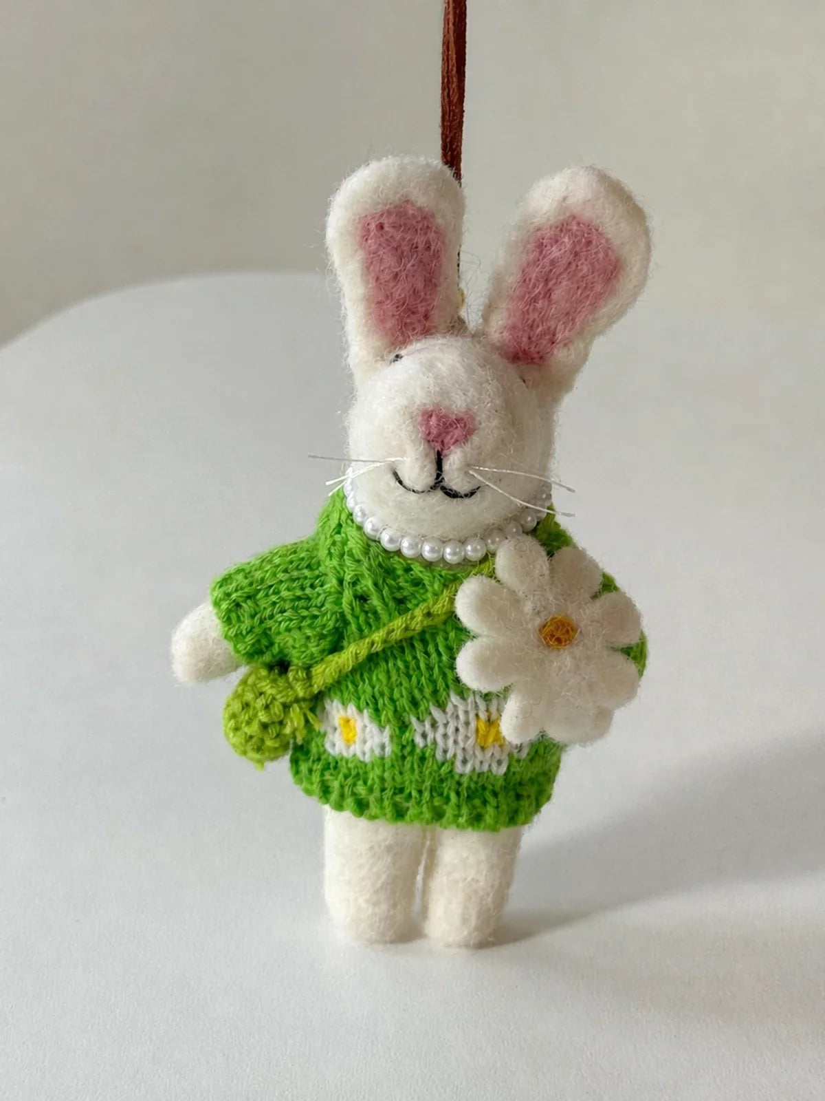 Close view of the knitted green dress, felt flower and pearl-style collar