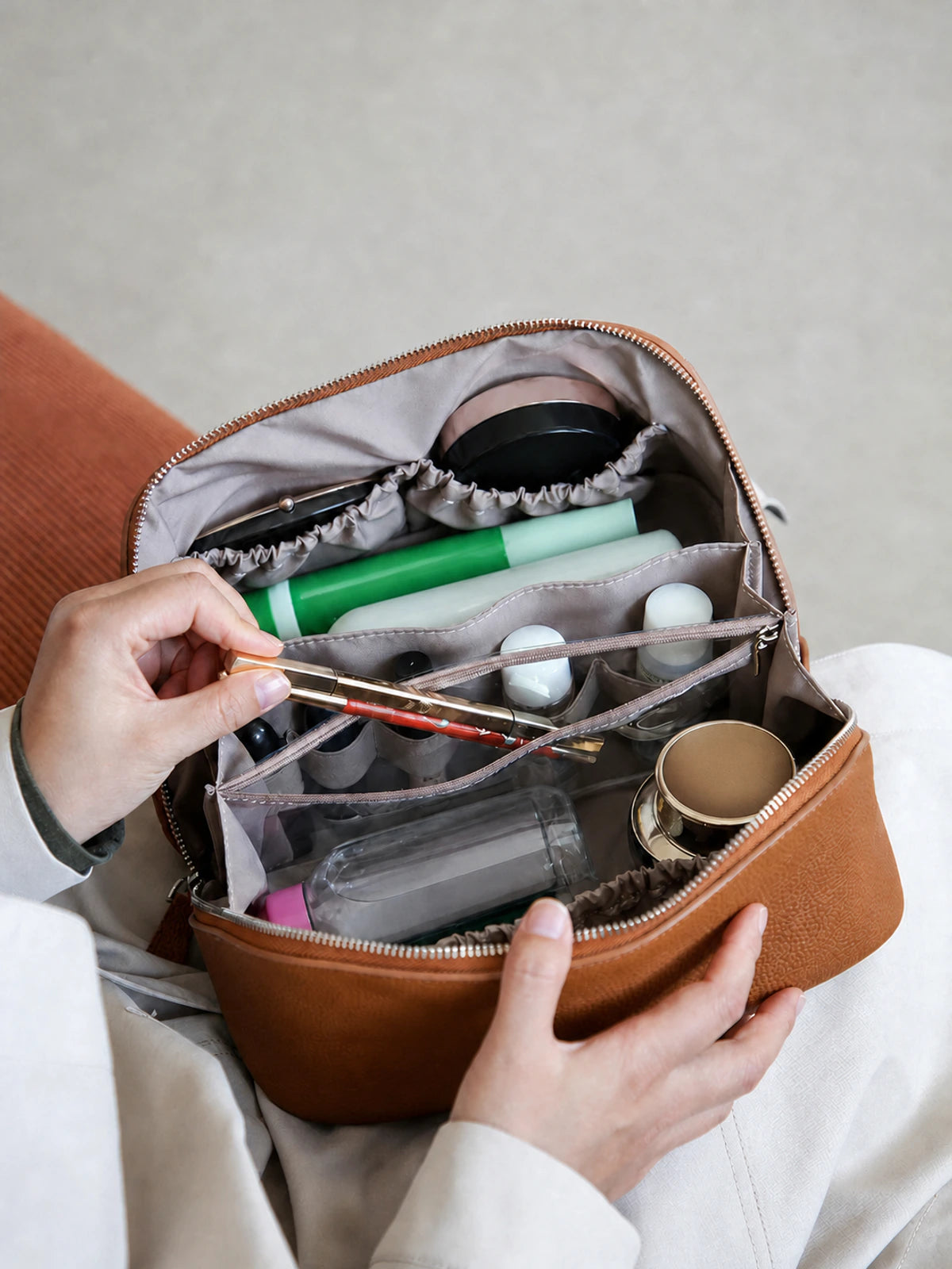 Open golden brown leather cosmetic case with built-in compartments and unbranded travel items