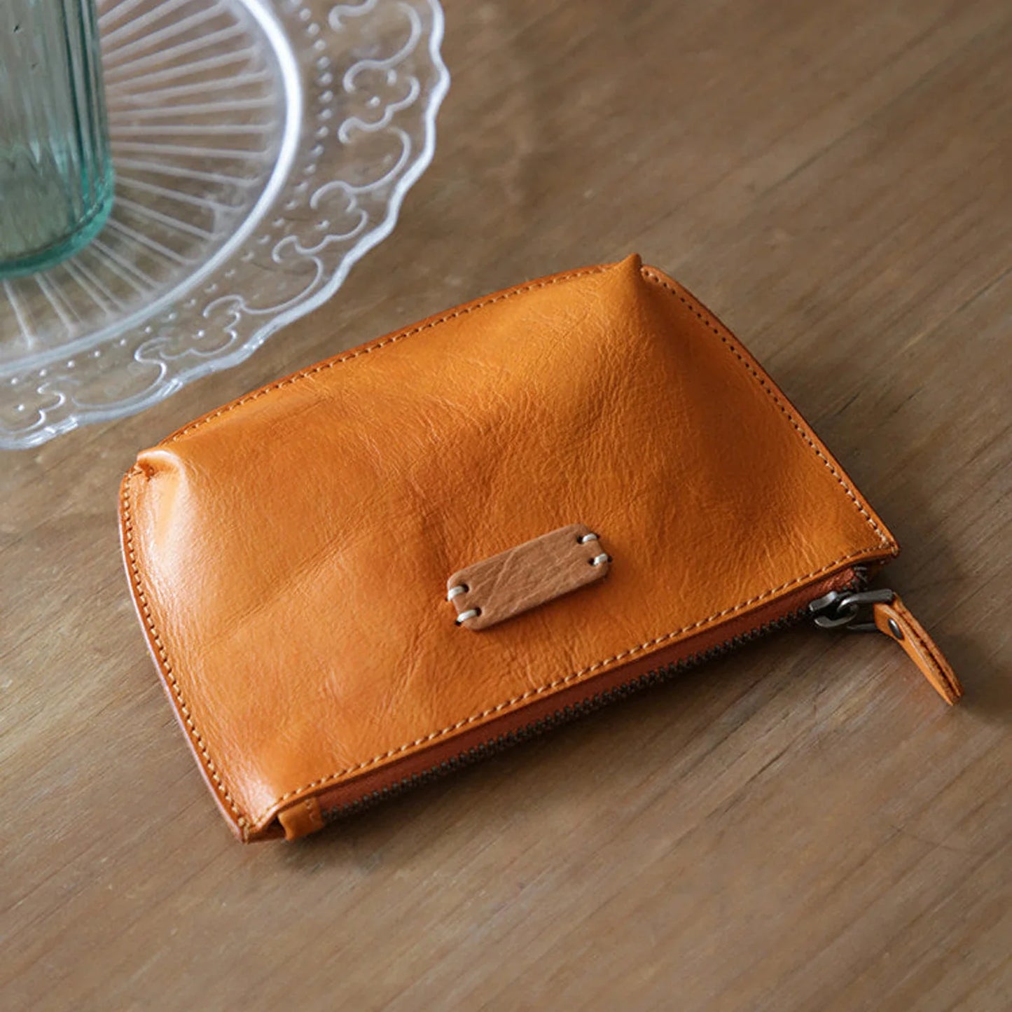 Sunset yellow vegetable-tanned leather cosmetic pouch on a wooden table