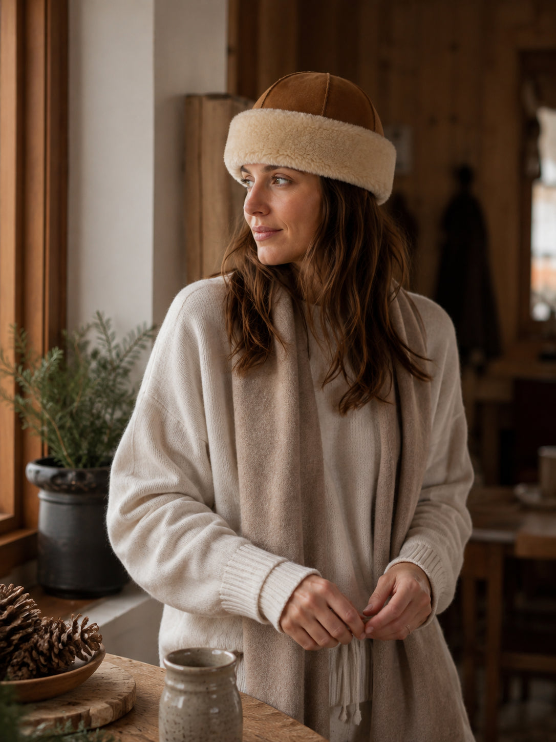 Woman wearing a camel and ivory wool shearling winter hat inside a lodge