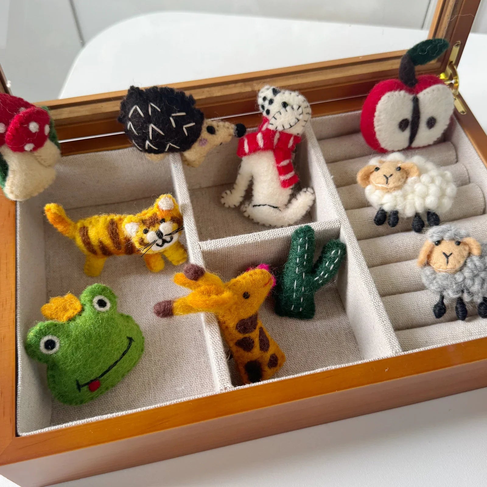 Handmade wool felt brooch assortment in a divided wooden tray
