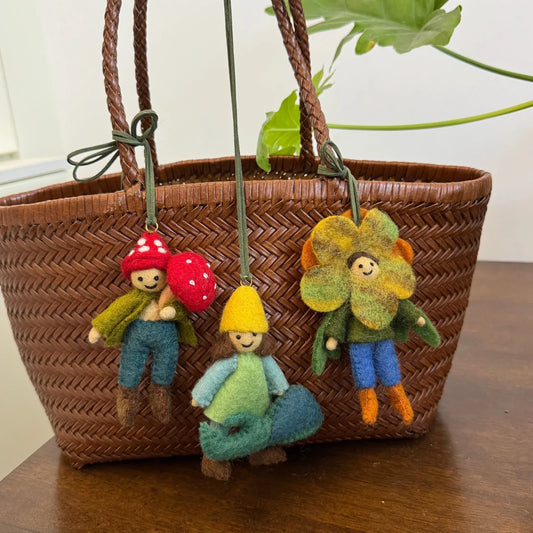 Lifestyle styling view of coordinated wool felt character charms on a woven tote
