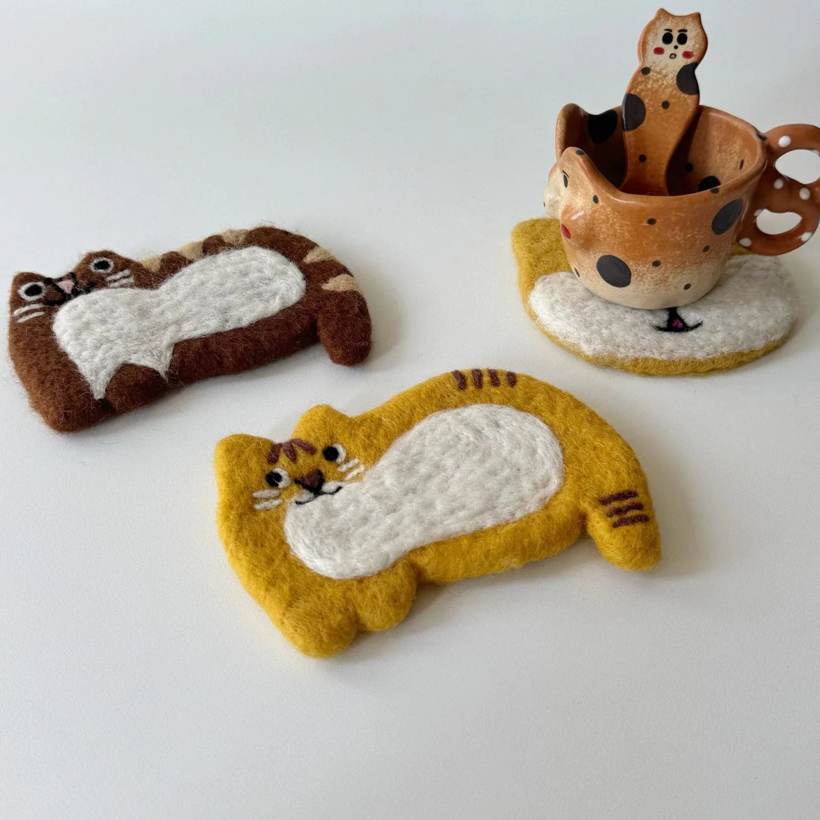 Yellow and brown cat wool felt coasters in a quiet tabletop setting