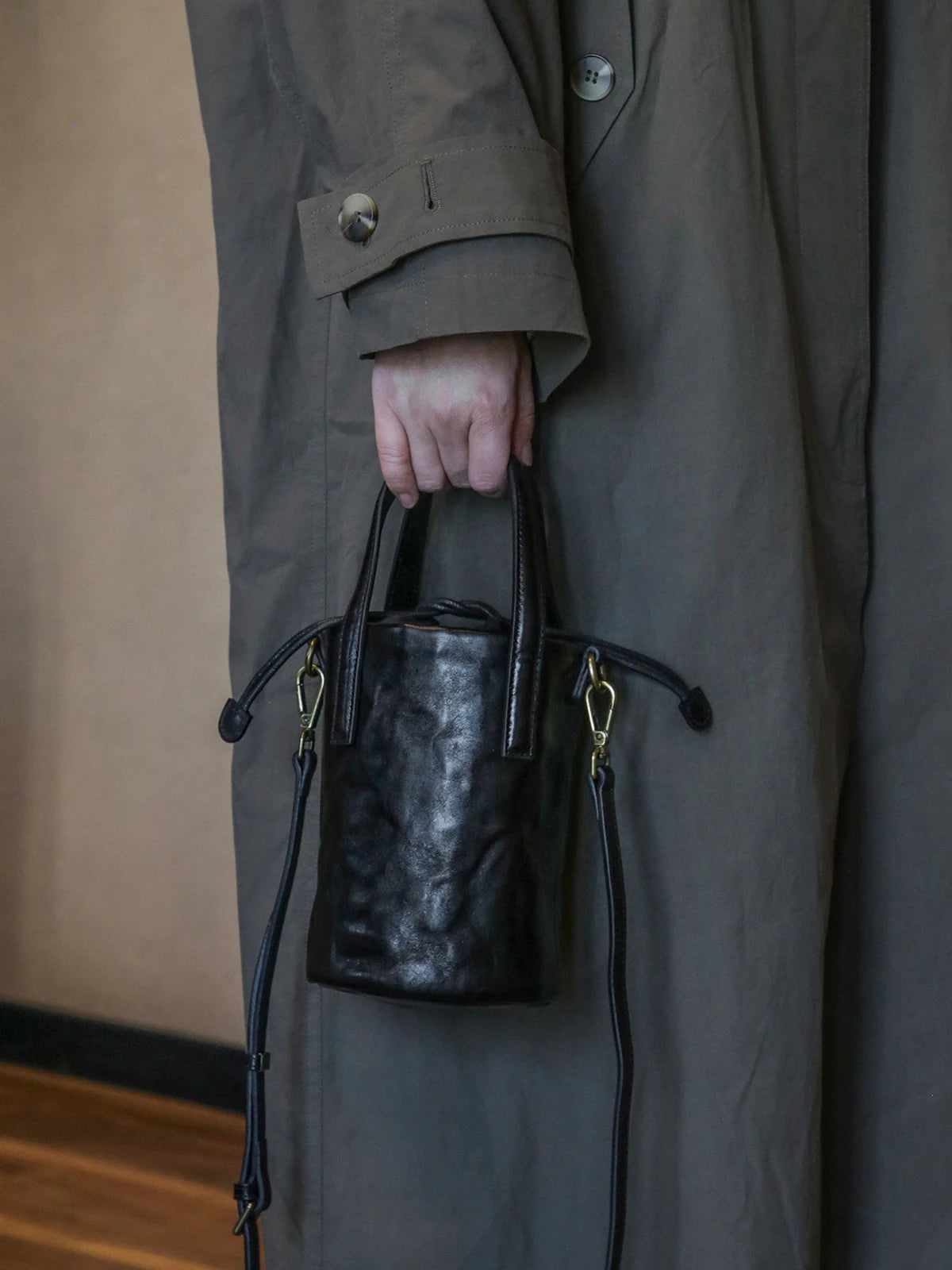 Women's black leather bucket bag carried by hand