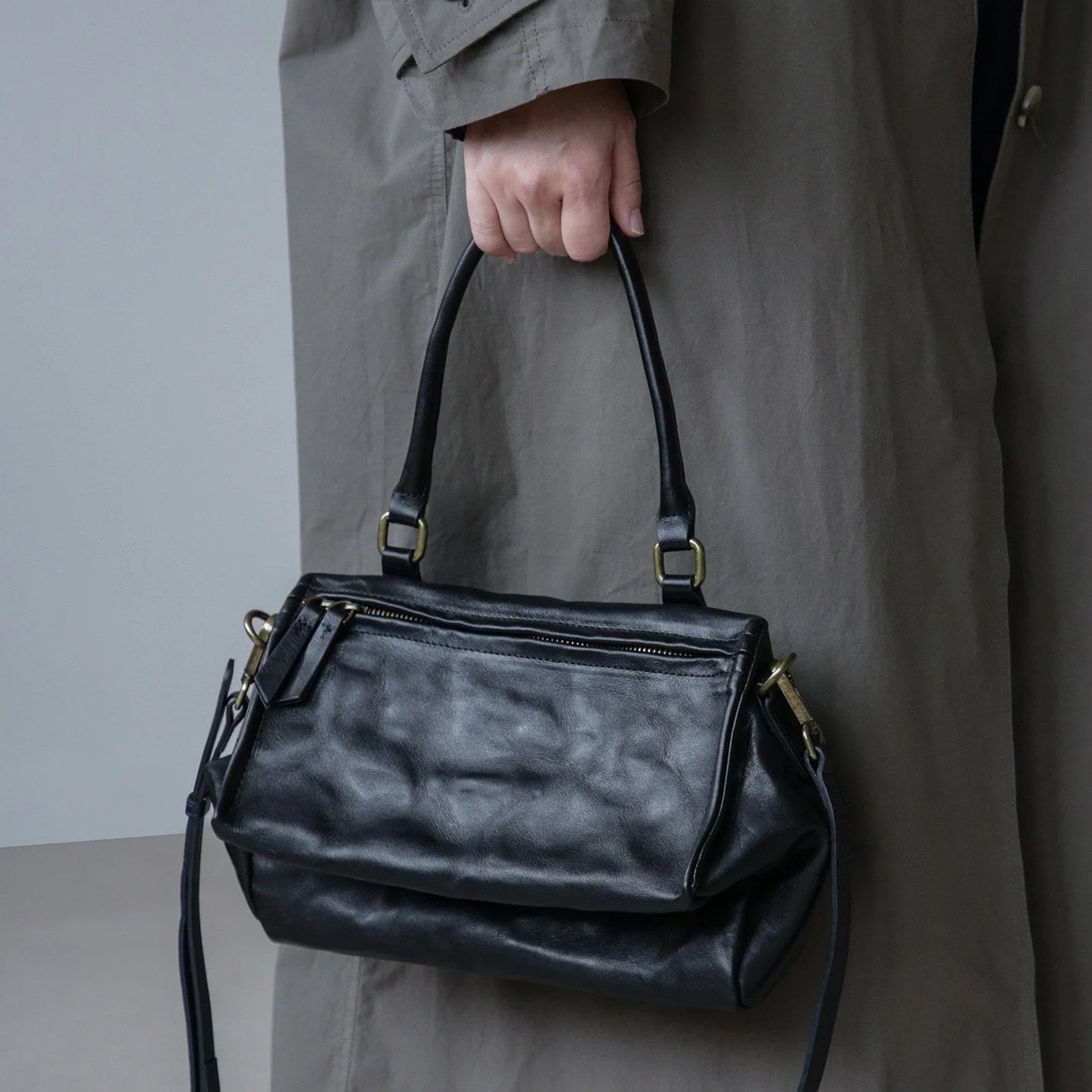 Black vegetable-tanned leather bag carried by the top handle