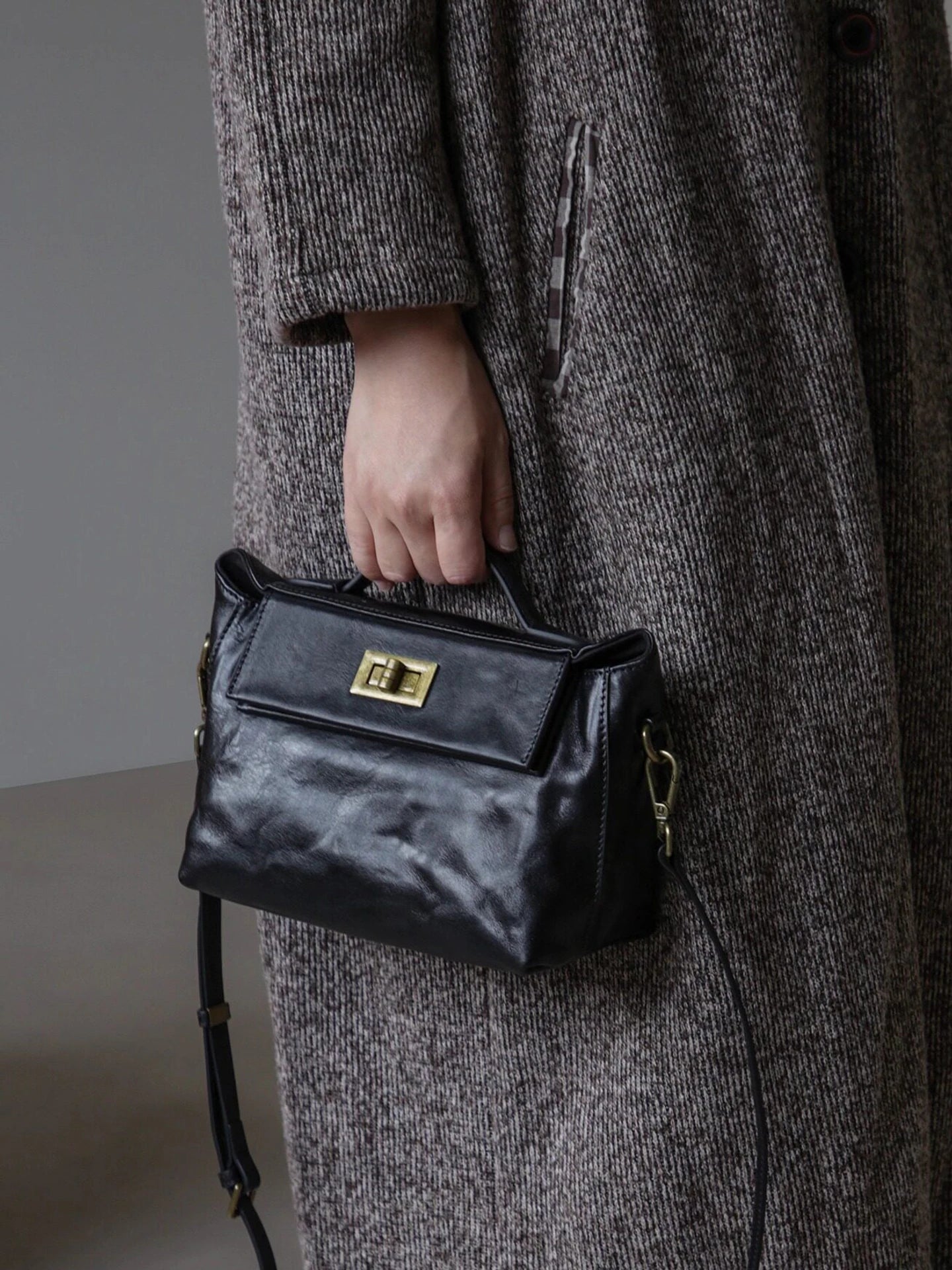 Black leather satchel showing the top handle, flap, and turn-lock closure
