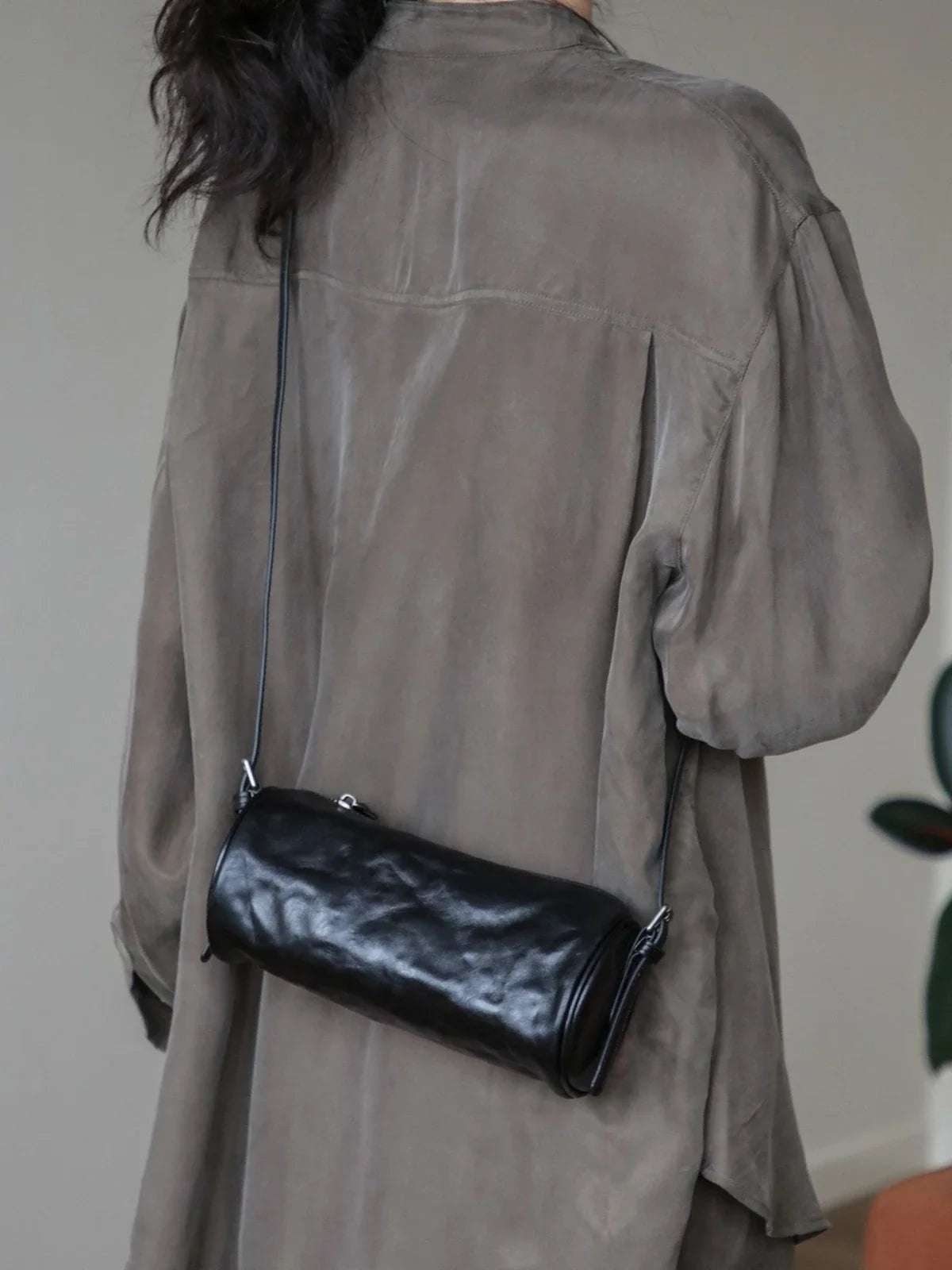 Black leather barrel shoulder bag worn at the back