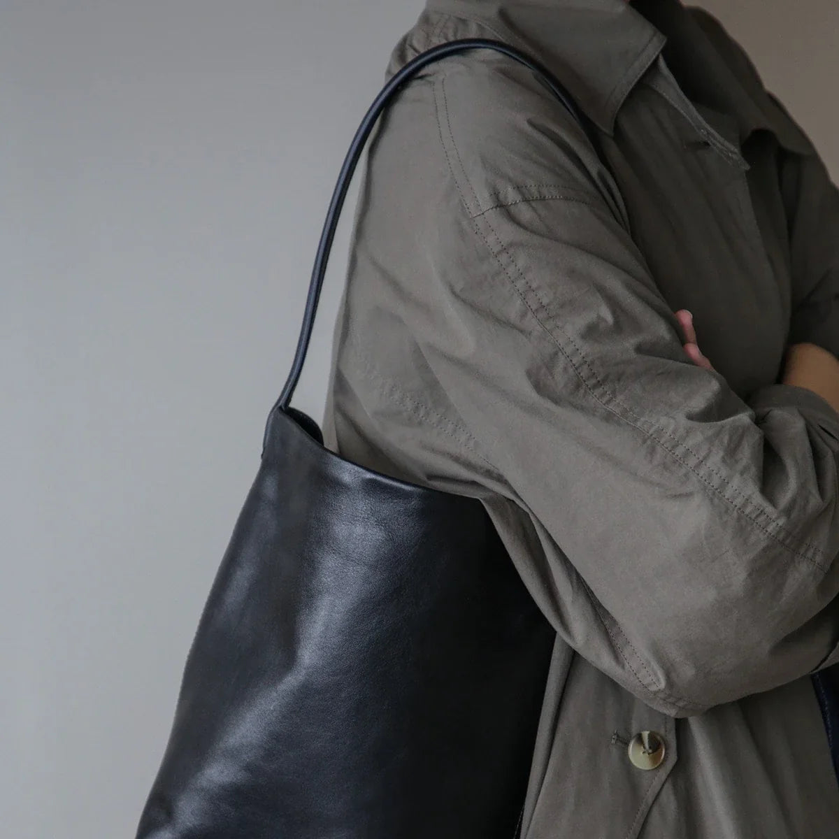 Women's black leather bucket bag in an everyday shoulder styling view