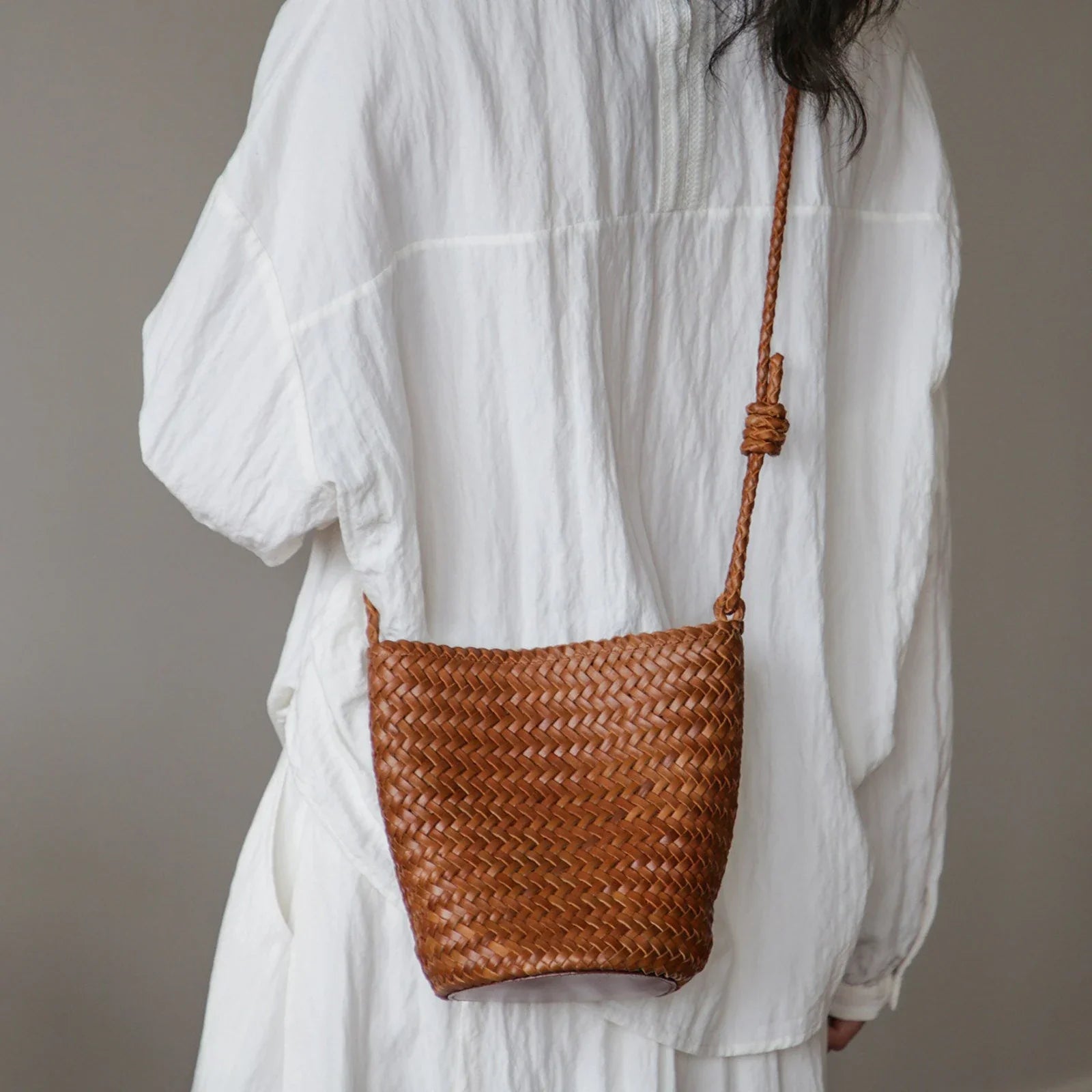 Brown woven leather bucket bag with adjustable knotted strap