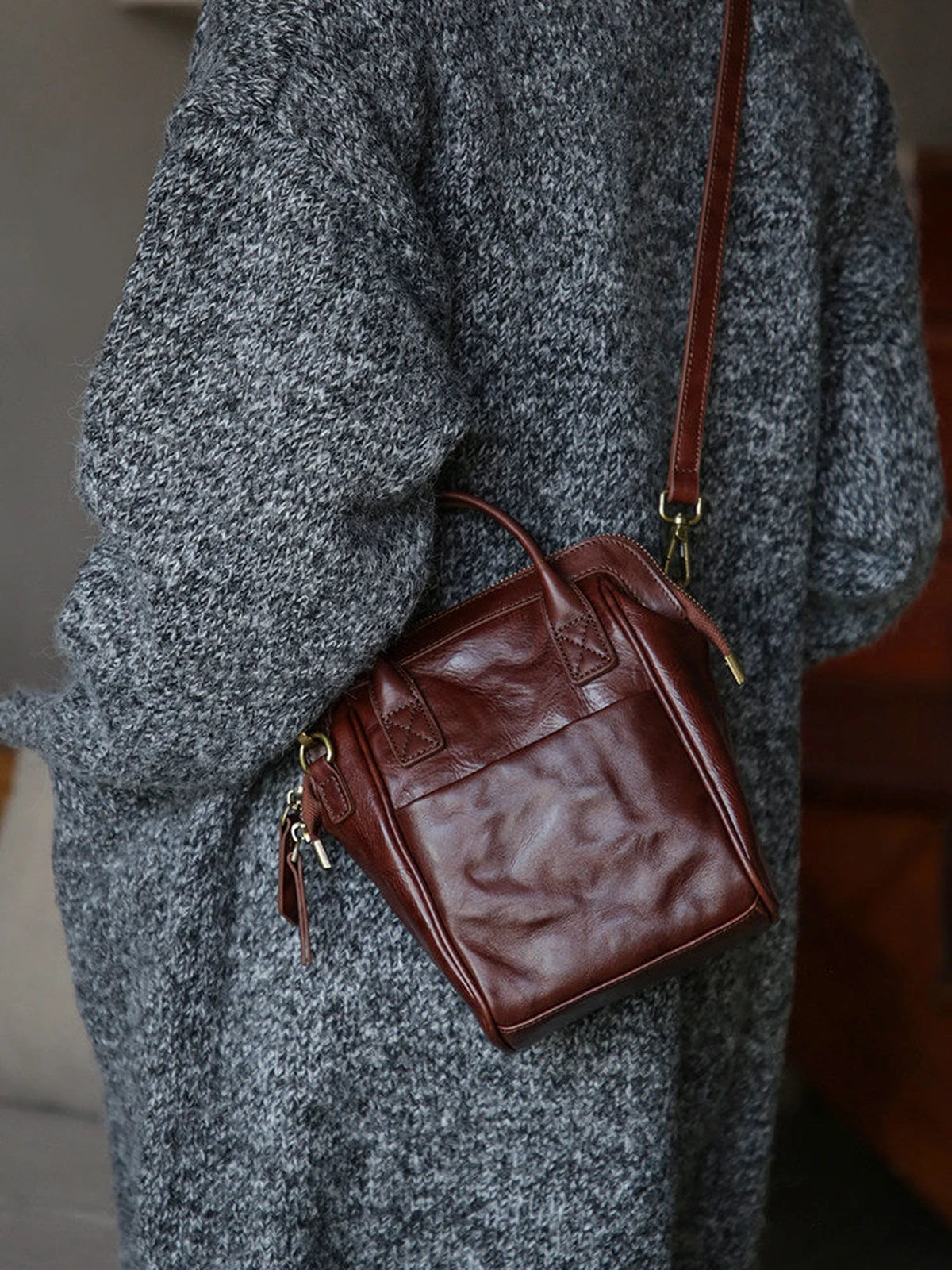 Coffee brown leather mini backpack styled as a crossbody bag