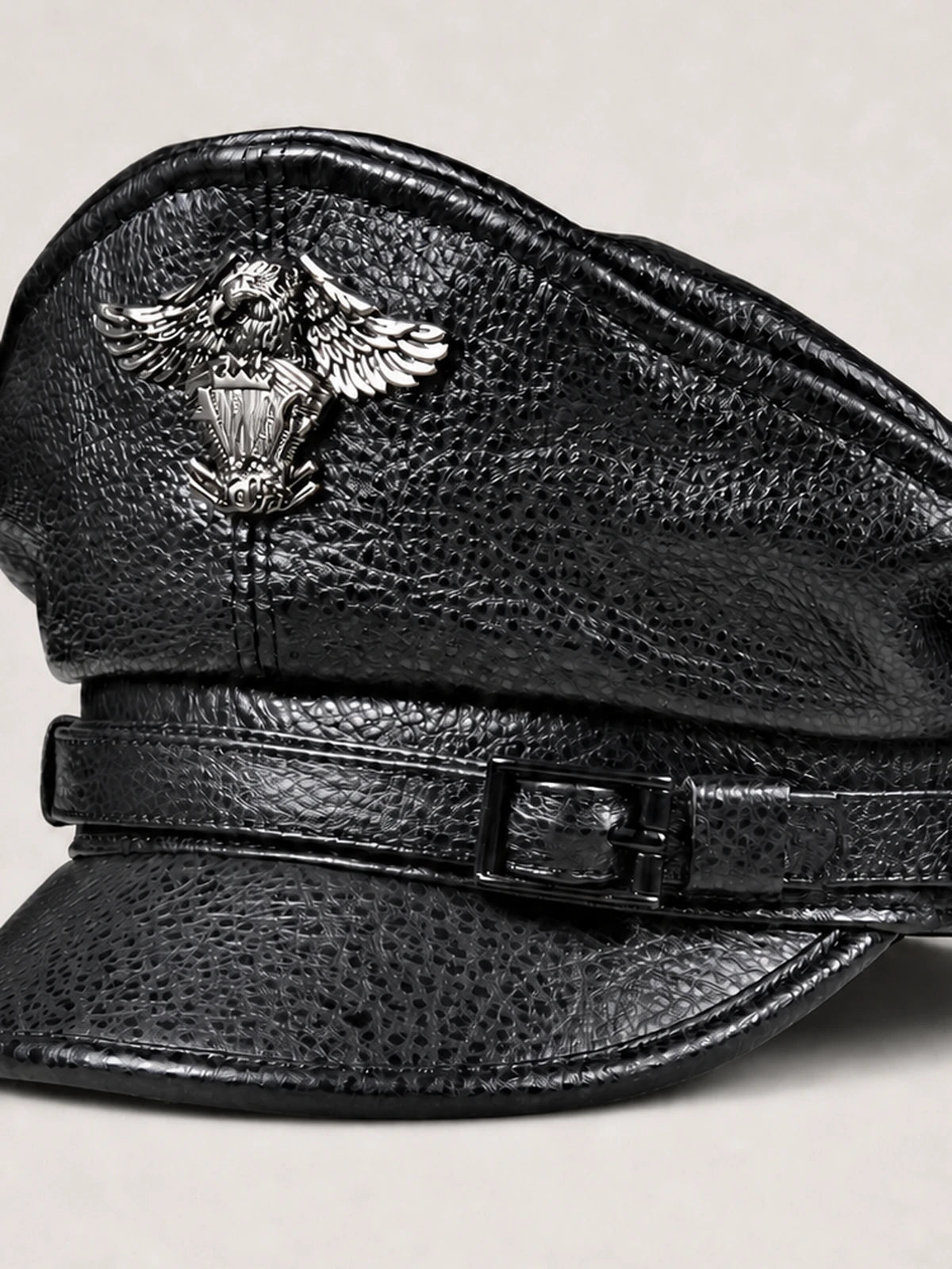 Close view of black cowhide leather grain, stitching, strap and decorative metal badge
