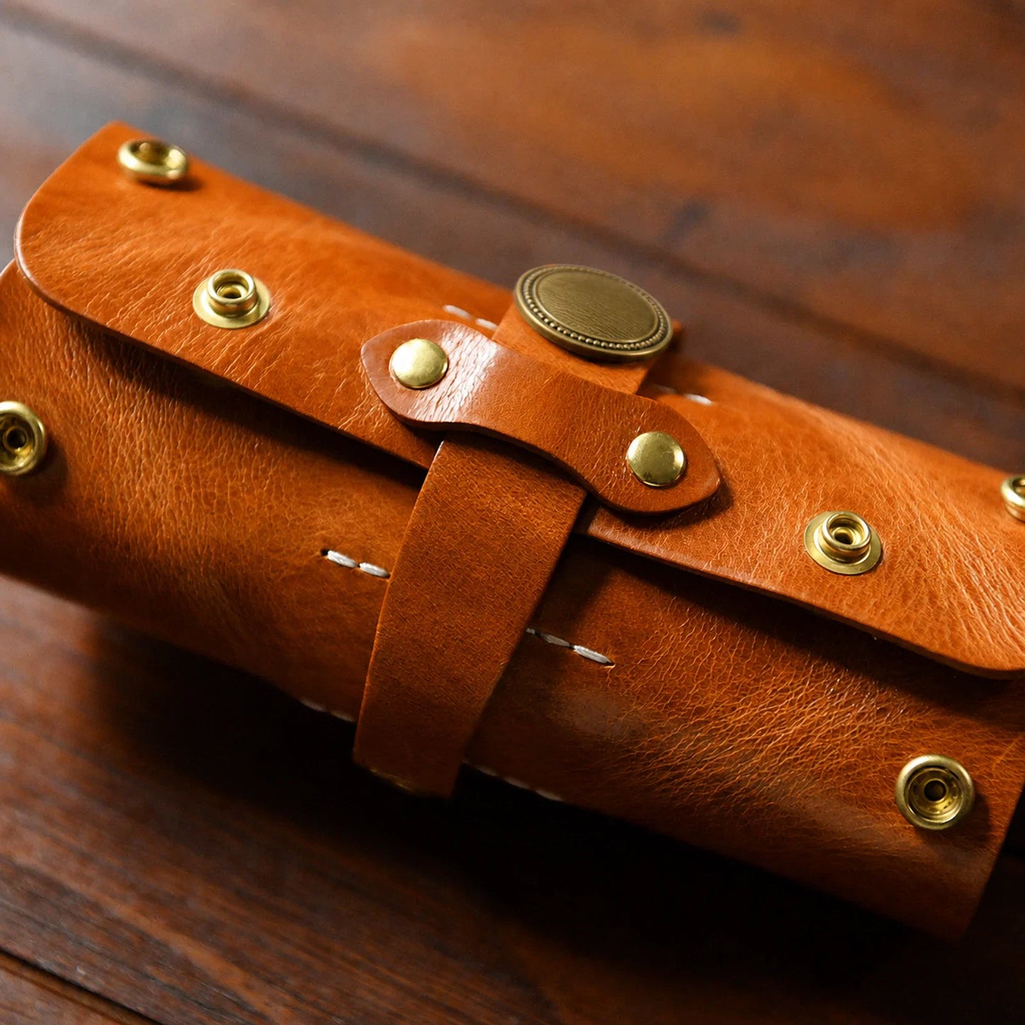 Close-up of hand stitching, leather grain and brass-tone snaps