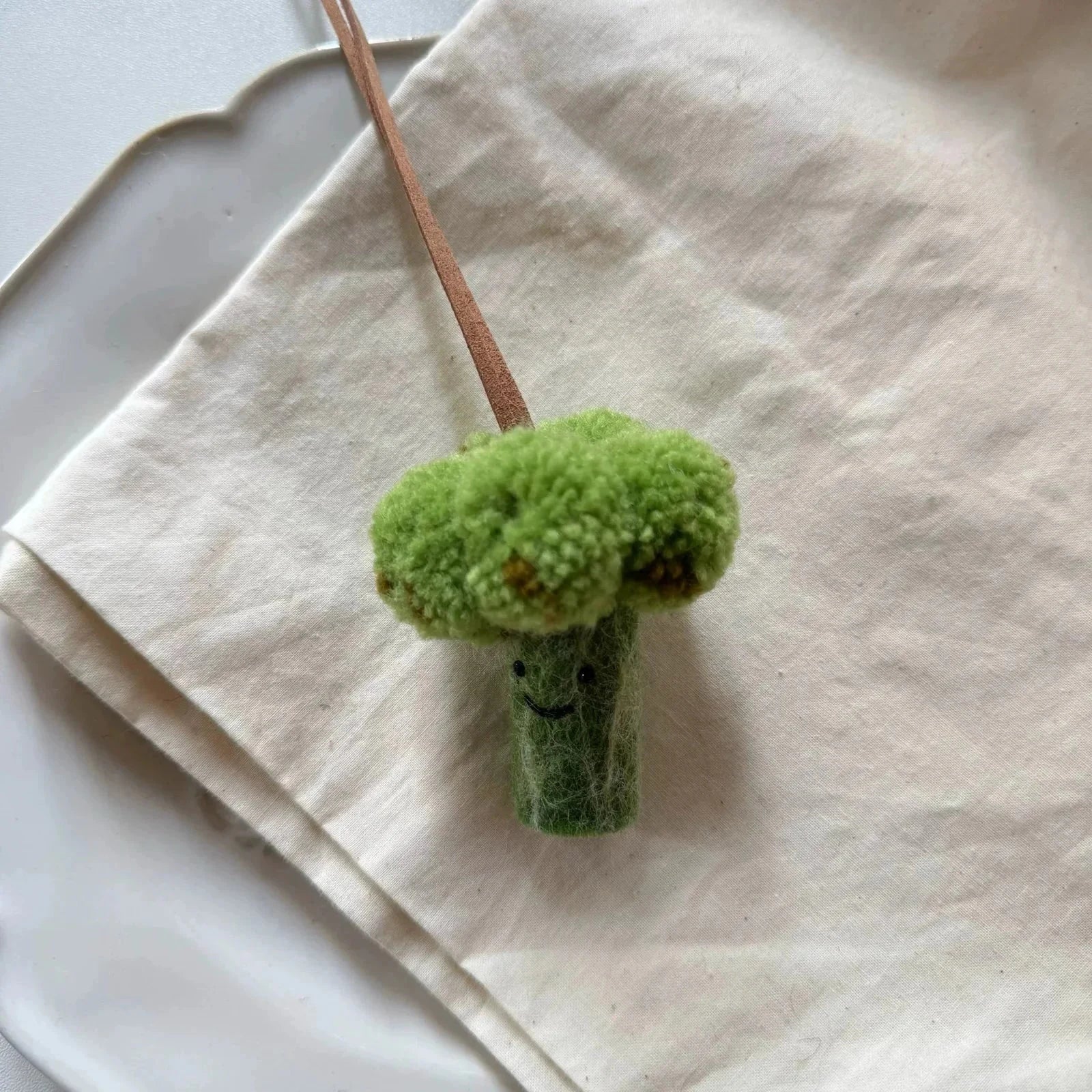 Handmade wool felt broccoli charm styled on natural linen