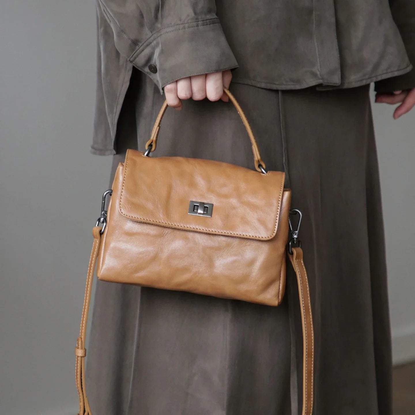 Coffee brown top-grain leather satchel carried by the top handle