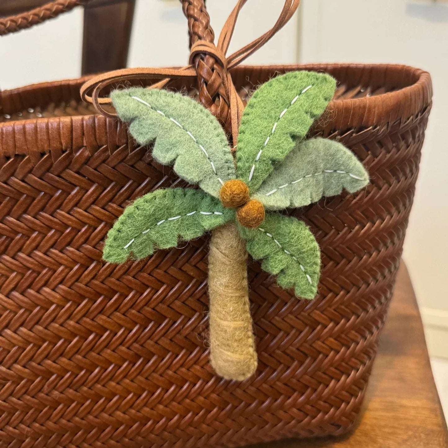 Full view of handmade wool felt palm tree bag charm with cord loop