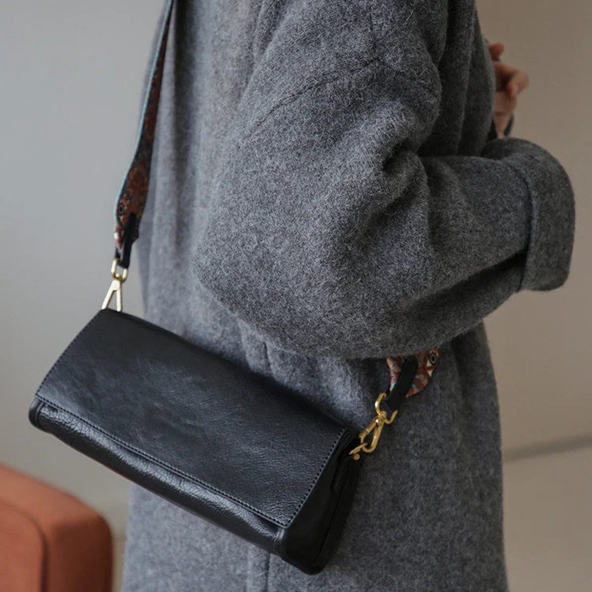 Black leather shoulder bag with a woven strap