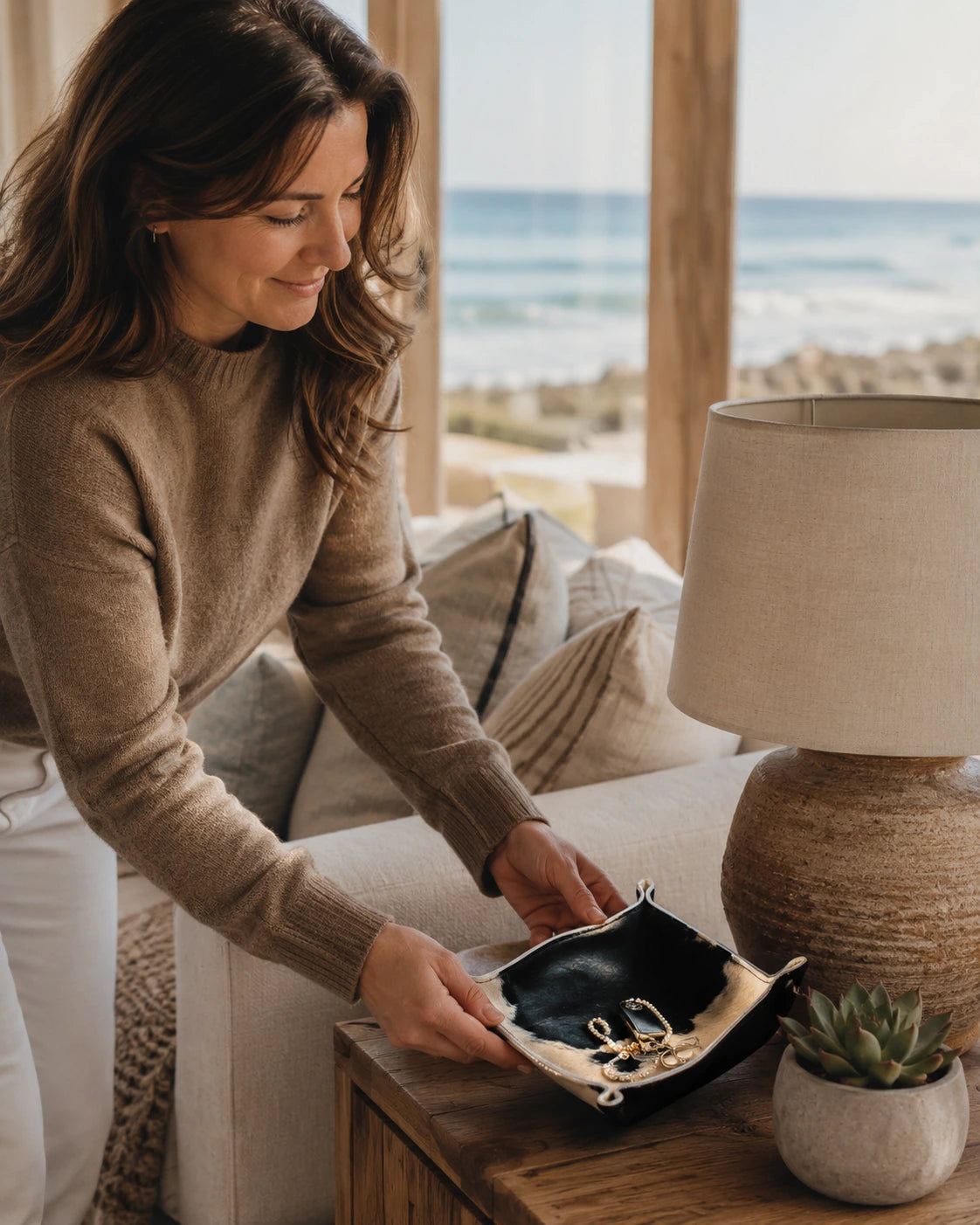 Woman setting a black and ivory genuine cowhide valet tray on a nightstand