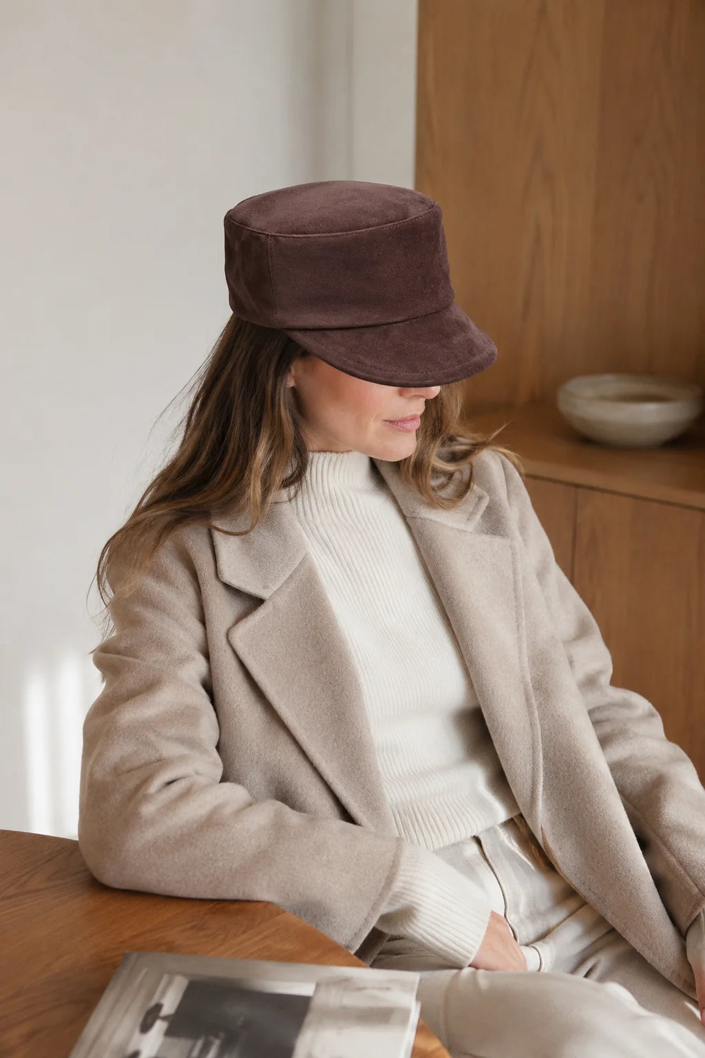Woman wearing a chocolate brown suede equestrian cap with neutral winter layers