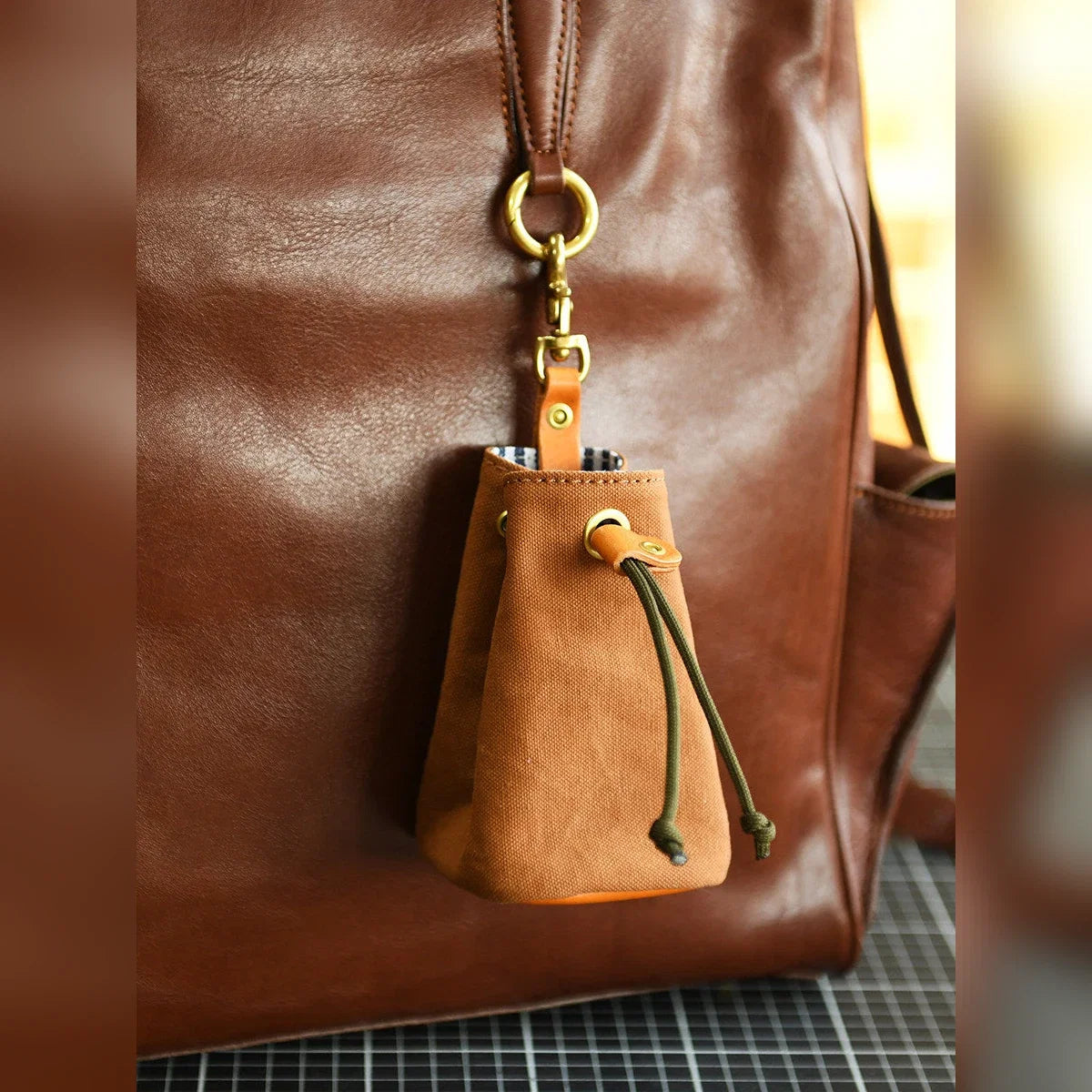 Drawstring storage pouch clipped to a leather bag
