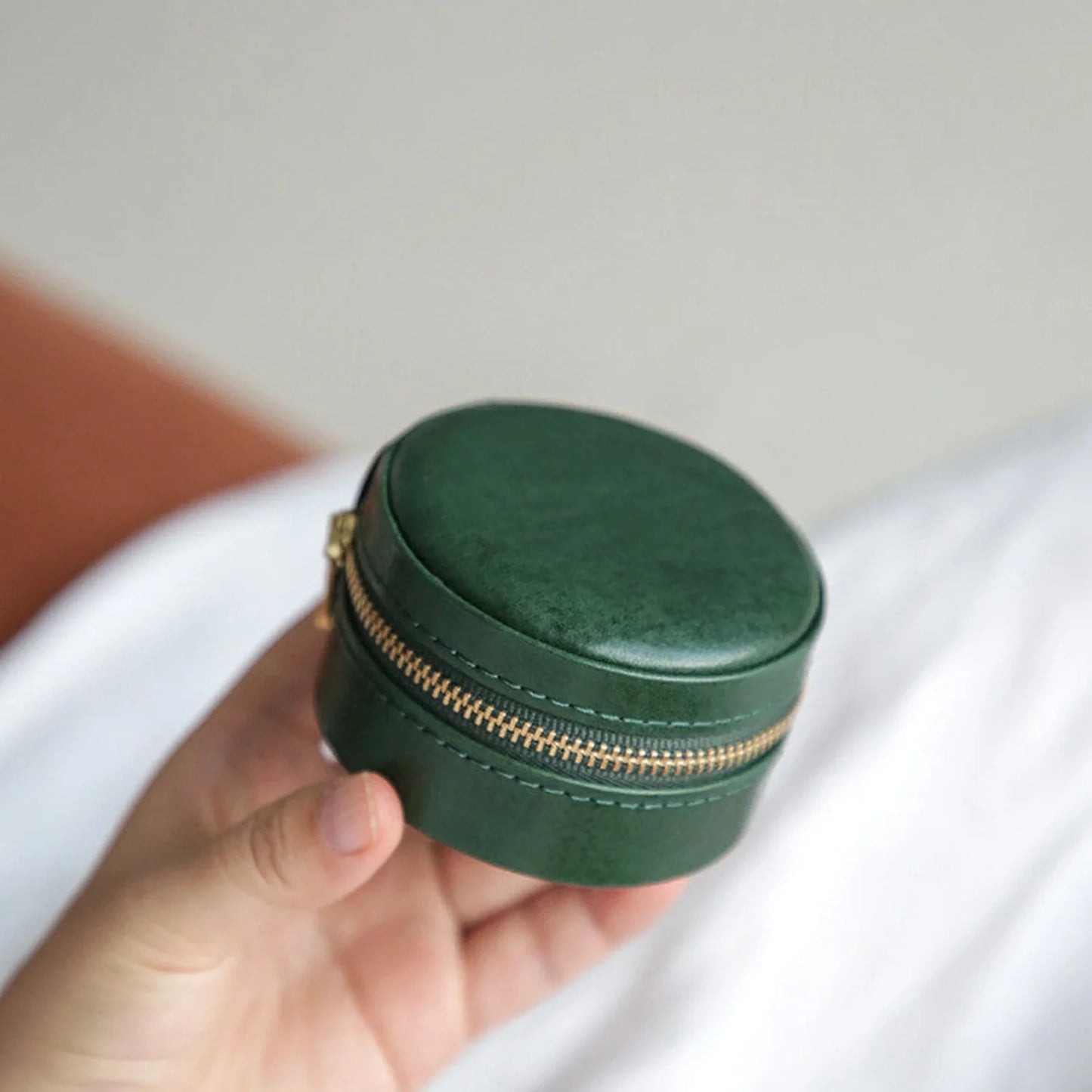 Forest Green round leather travel jewelry case shown in hand