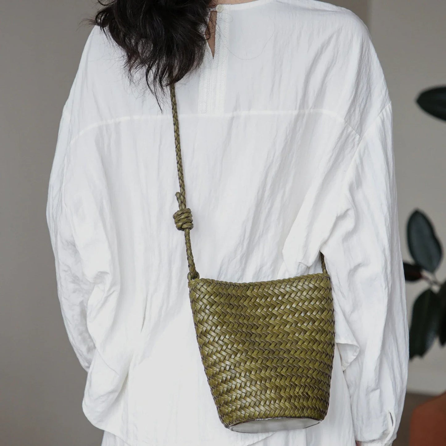 Olive green woven leather bucket bag with adjustable knotted strap
