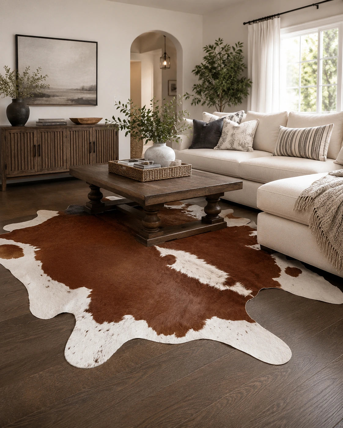 Rich brown and ivory genuine cowhide rug styled beneath a wood coffee table