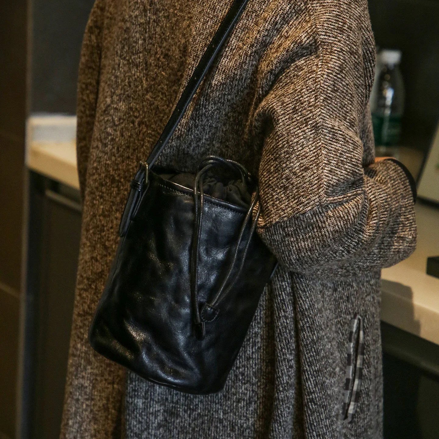 Black top-grain leather bucket bag worn over the shoulder