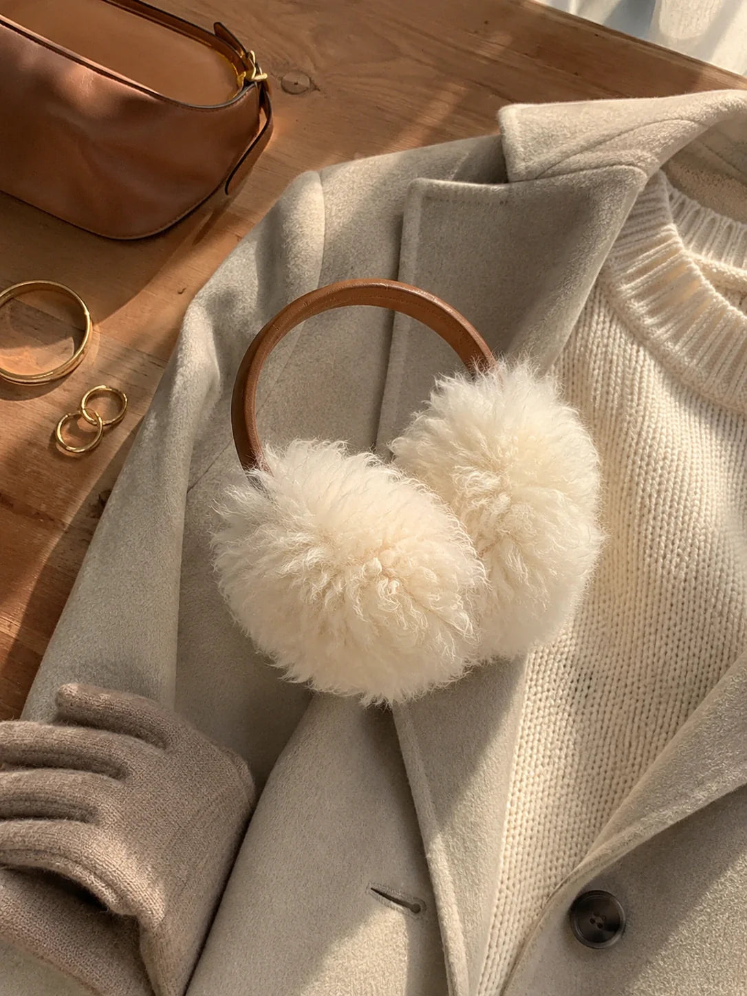 White wool earmuffs with a brown headband styled with neutral winter layers
