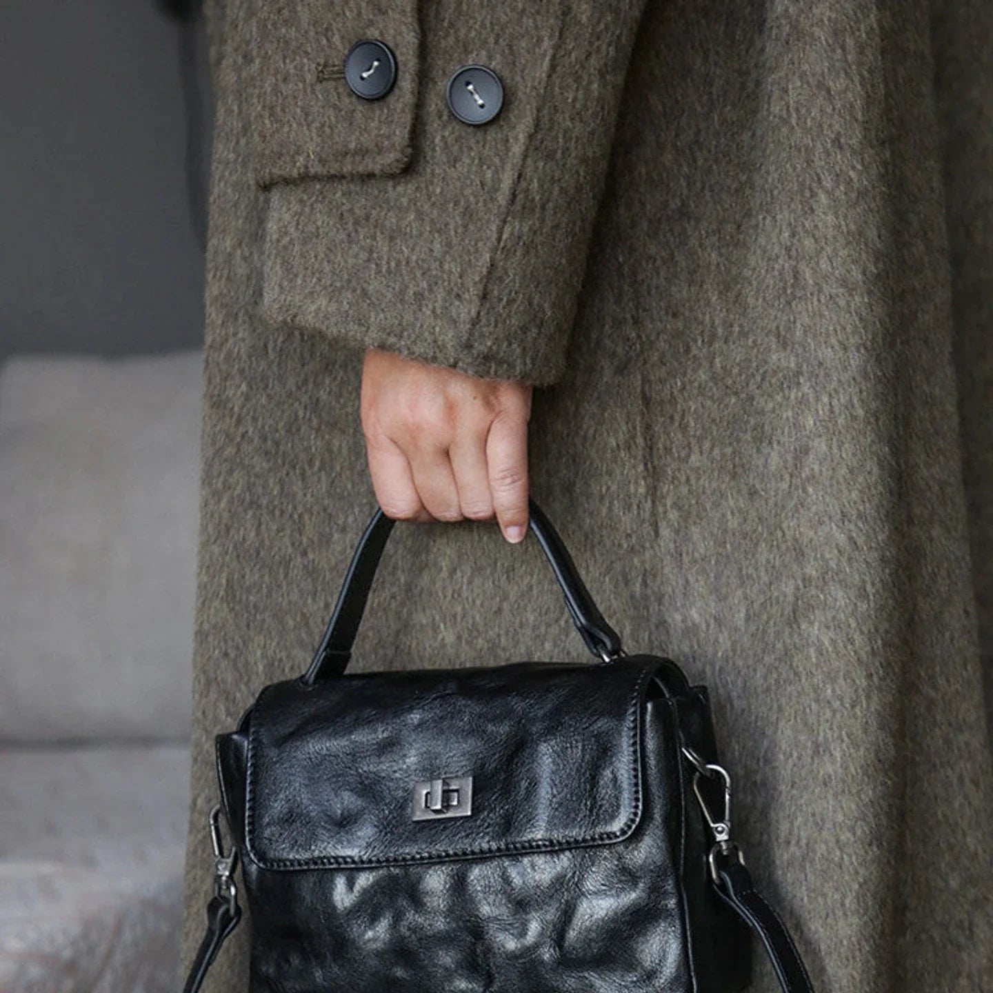 Black top-grain leather satchel carried by the structured handle