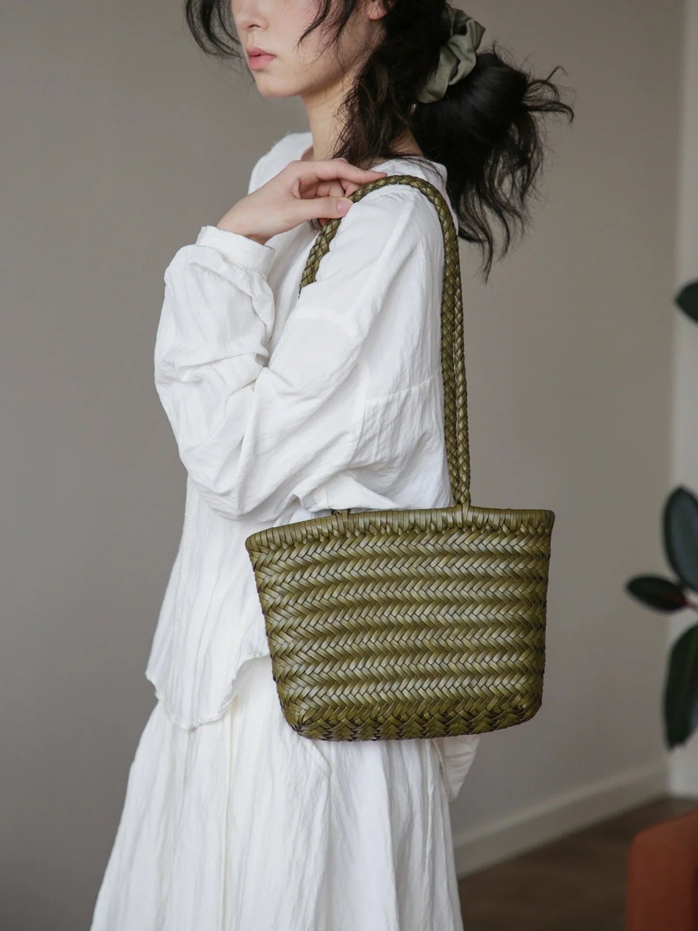 Olive green woven leather shoulder bag worn on the shoulder