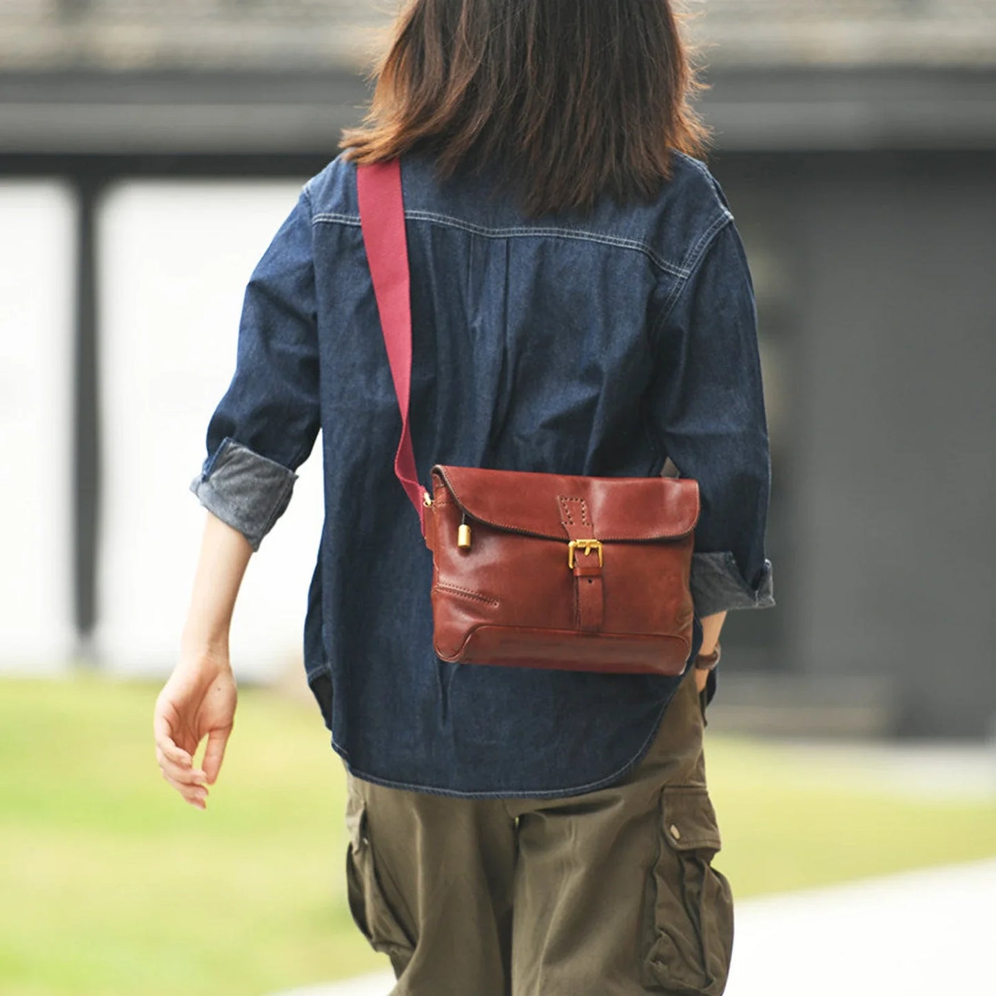 Burgundy leather messenger bag worn over the shoulder, rear view