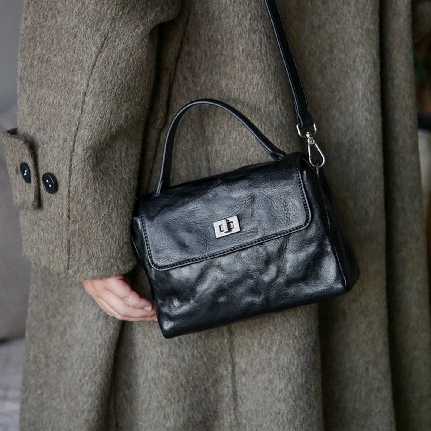 Black leather satchel worn with the detachable crossbody strap