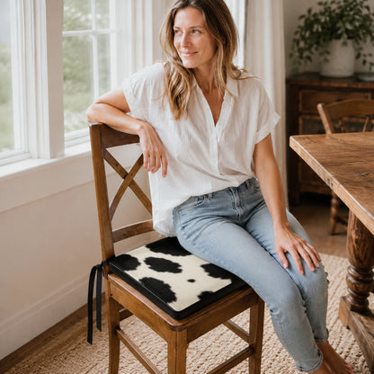 Woman seated on a black and ivory genuine cowhide chair pad at a wood dining table
