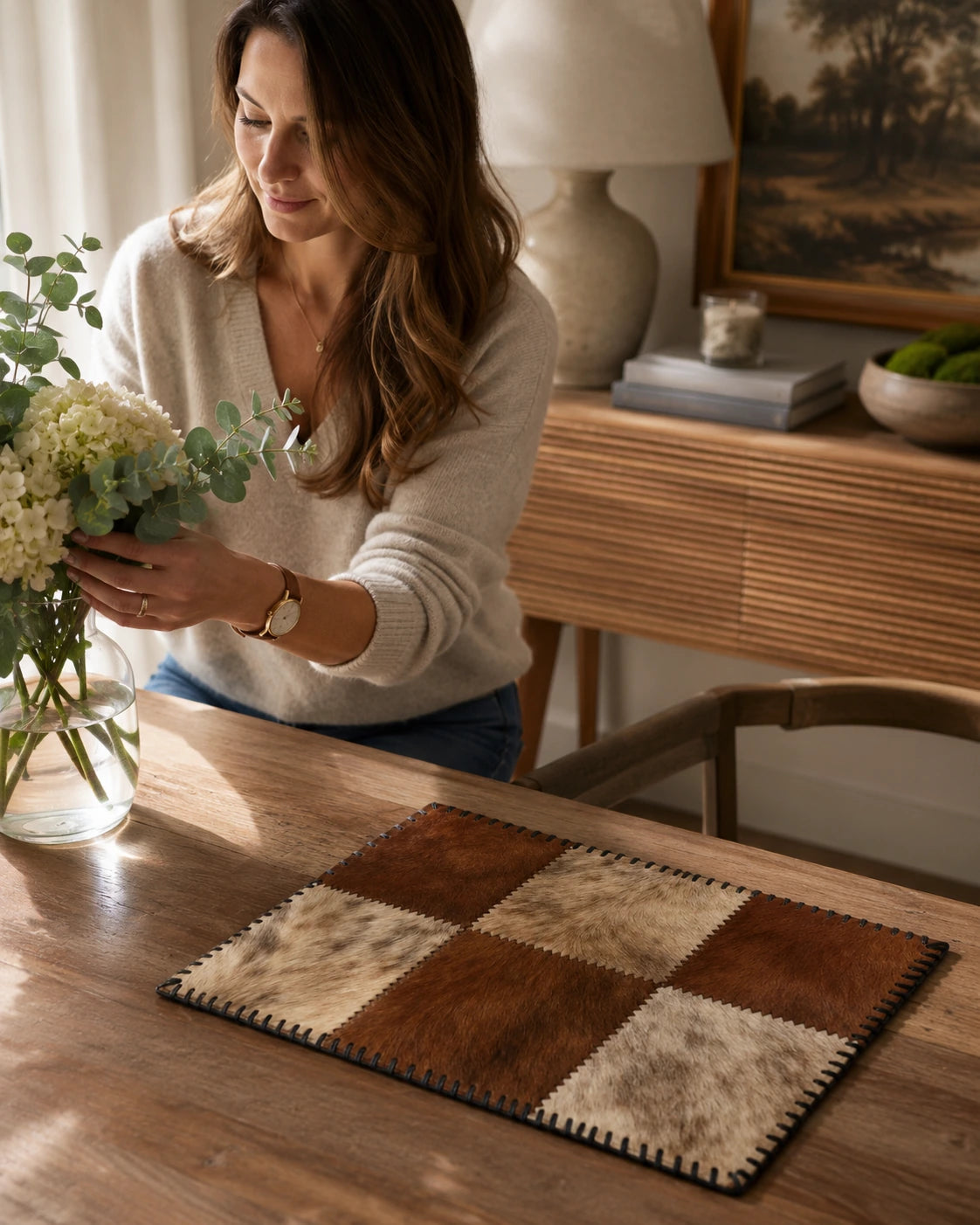 Woman arranging flowers beside a genuine cowhide patchwork placemat