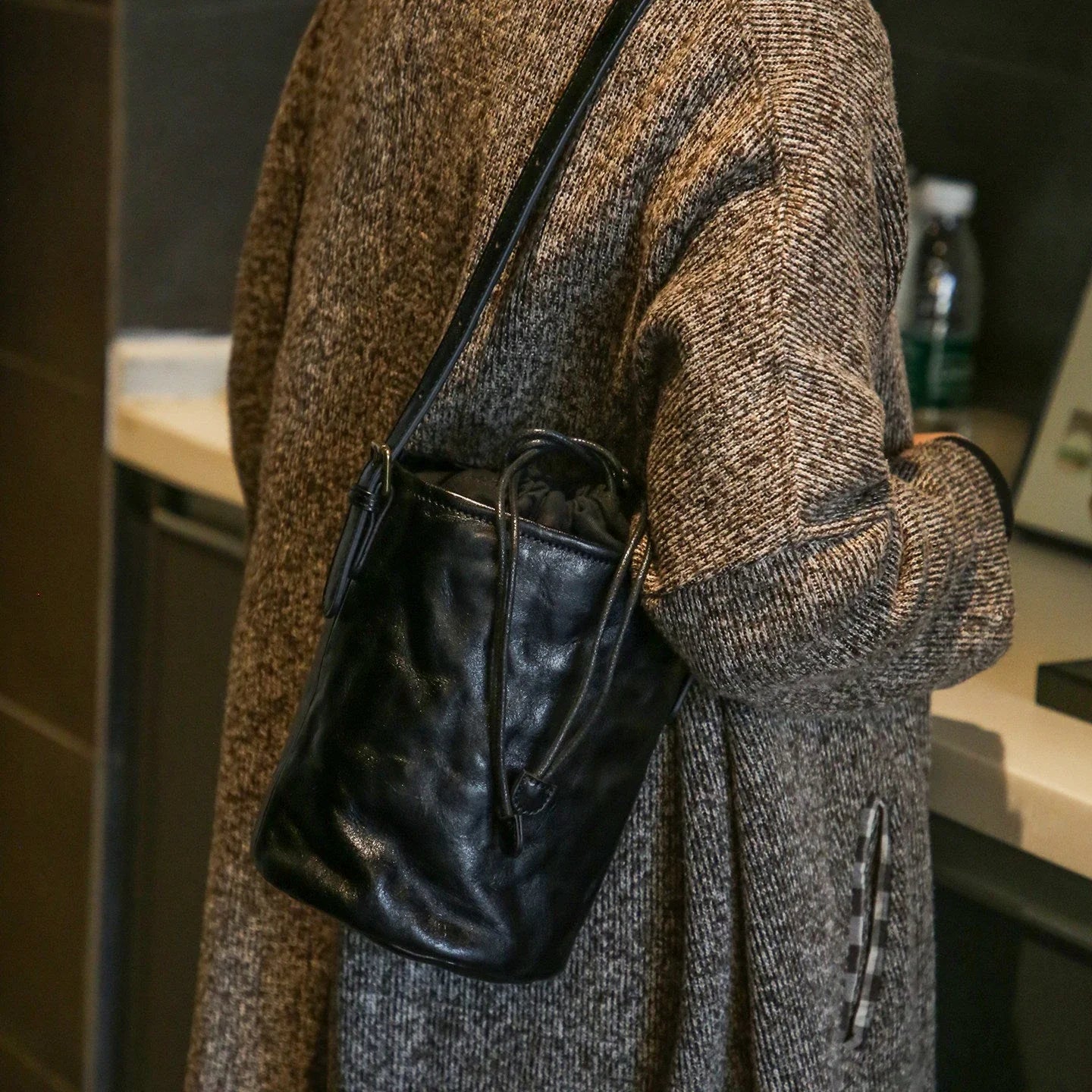 Black top-grain leather bucket bag styled crossbody