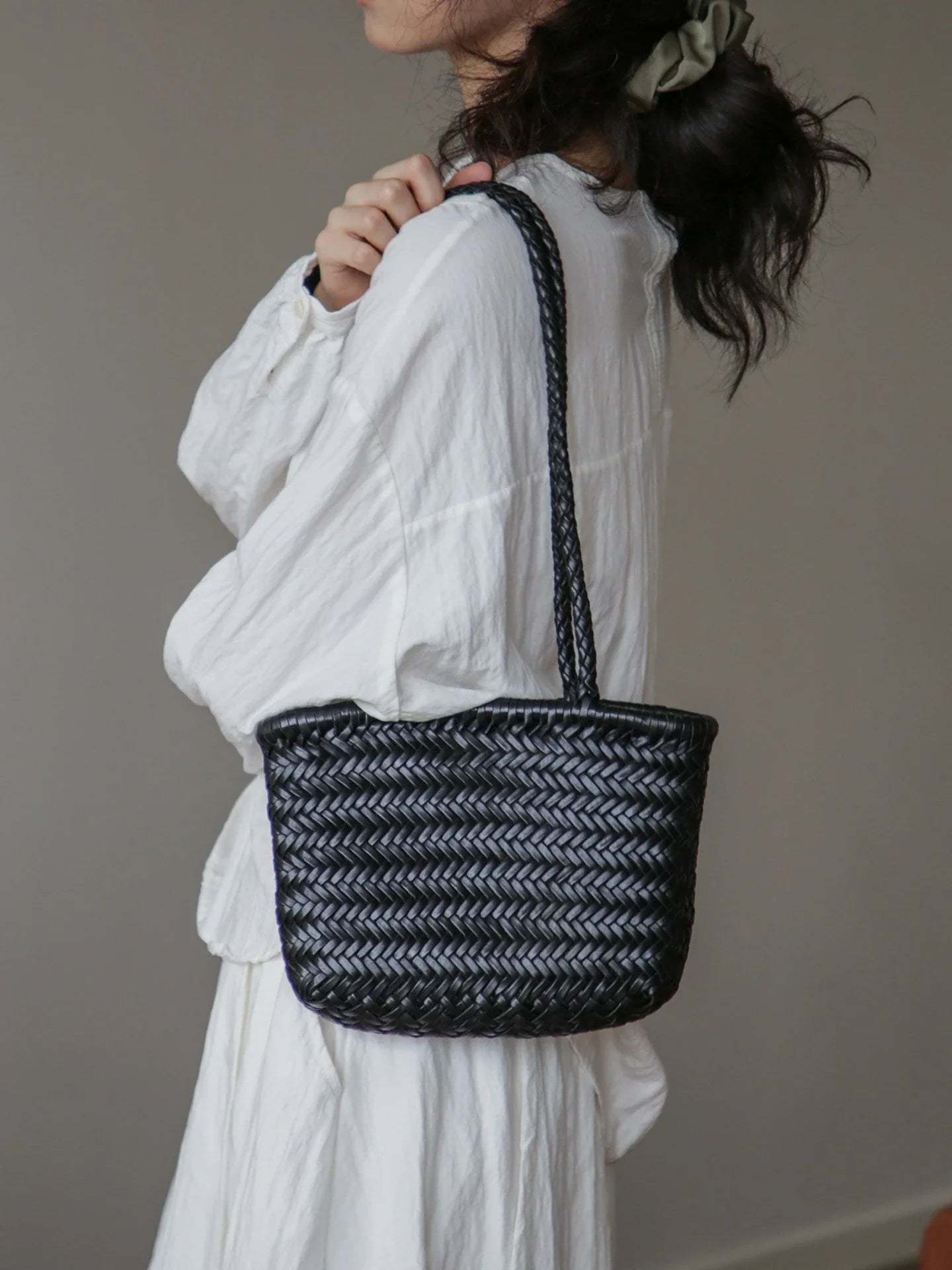 Black woven leather shoulder bag in a lifestyle view