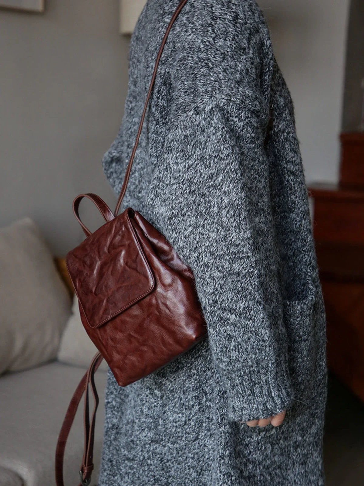 Coffee-brown mini leather backpack carried by its top handle