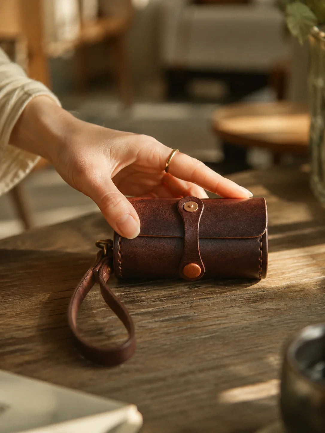 Vintage brown cowhide wristlet case shown in hand
