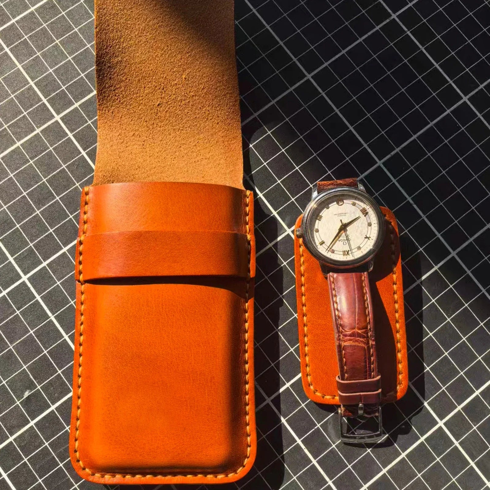 Open leather watch pouch pocket shown beside a wristwatch