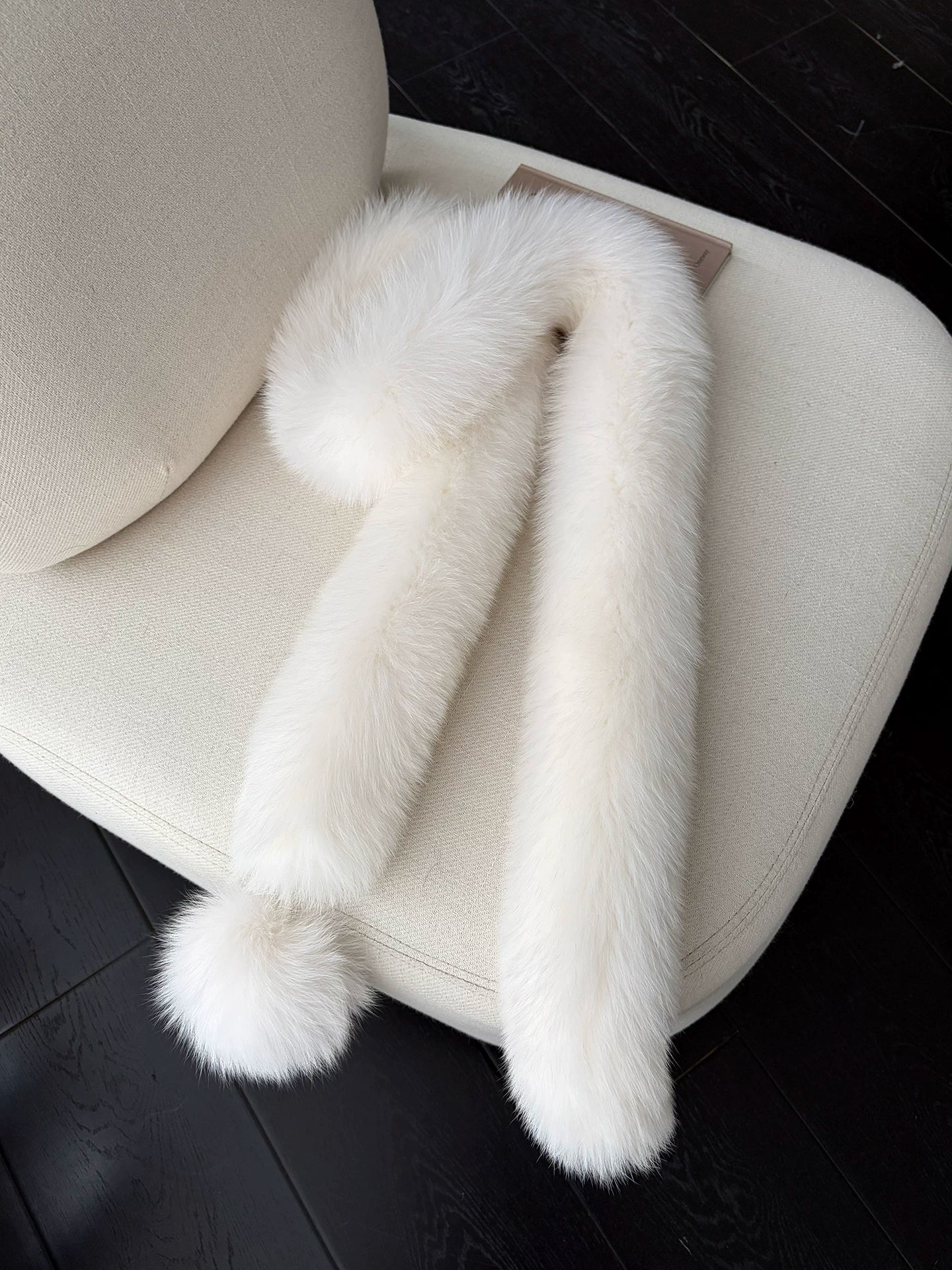 Cream Beige fox fur long scarf with pom-pom arranged on a cream chair