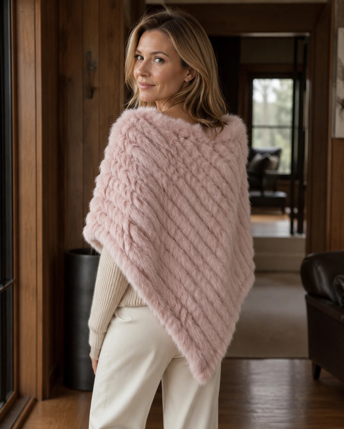 Apricot pink rabbit fur knit poncho worn in a warm interior