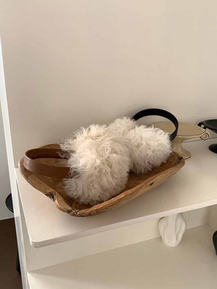 Camel and black wool earmuffs arranged together on a wooden tray