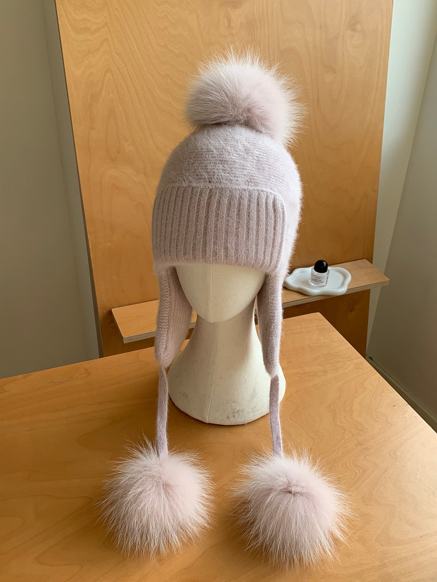 Rose pink knit earflap pom-pom hat displayed on a mannequin