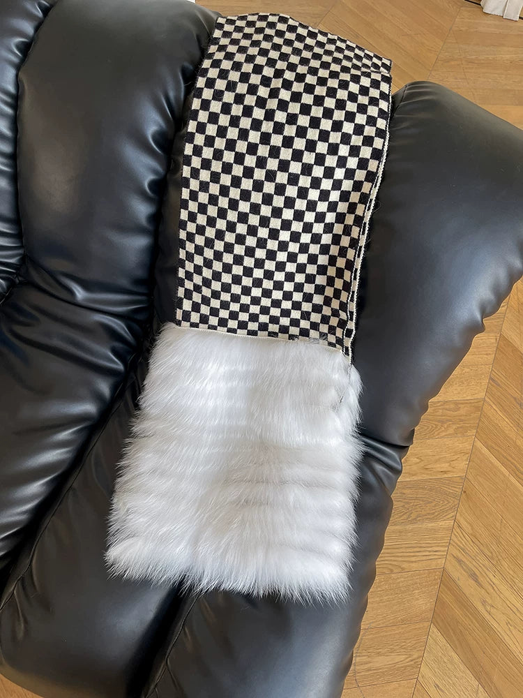 Black-and-white checkerboard fox fur scarf displayed on a black chair, vertical product view
