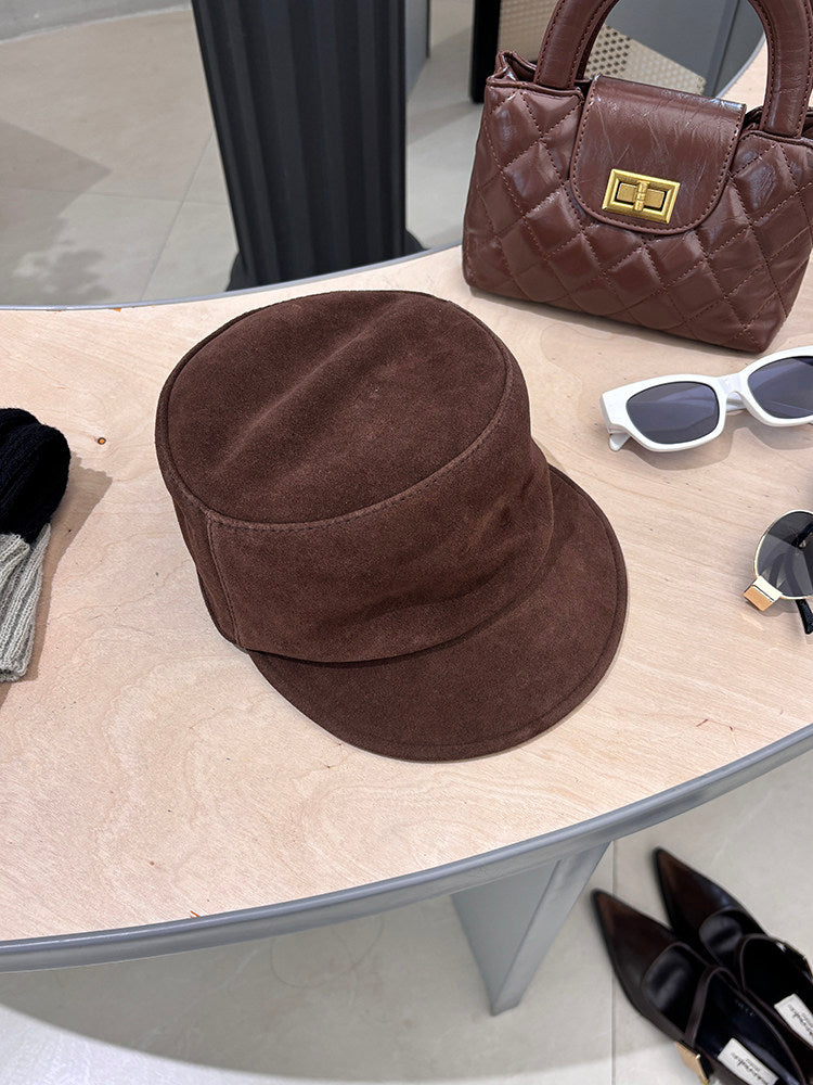 Brown suede lambskin leather equestrian riding cap styled on a tabletop