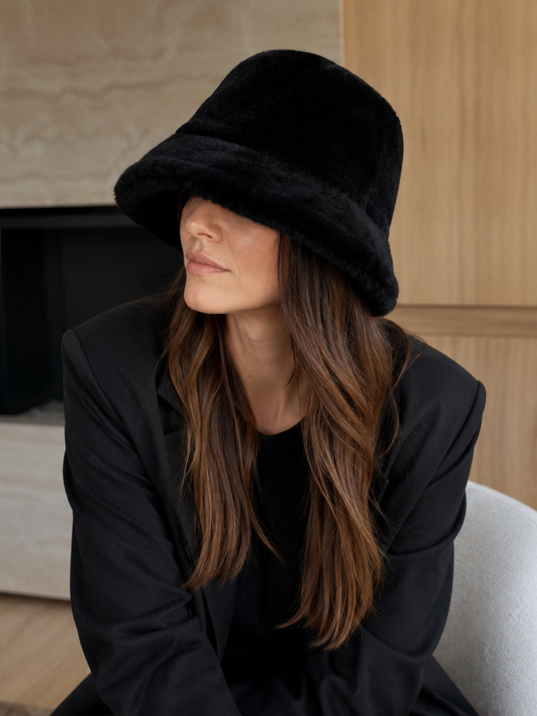 Person styling a Black genuine leather bucket hat indoors