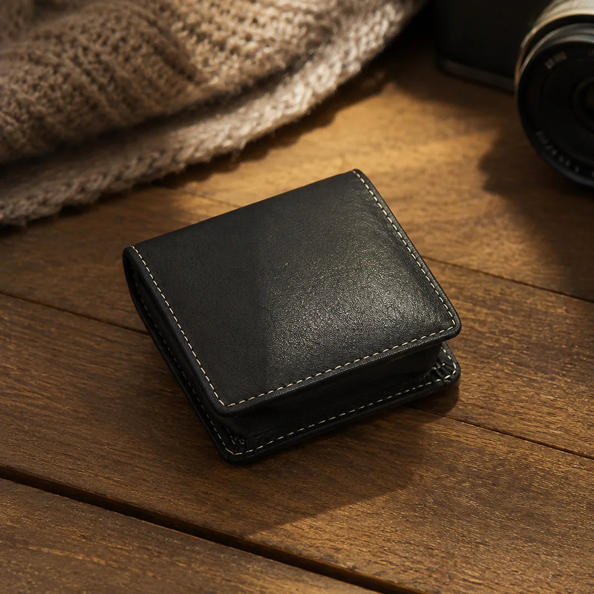 Black leather coin purse with contrast stitching on a wood table